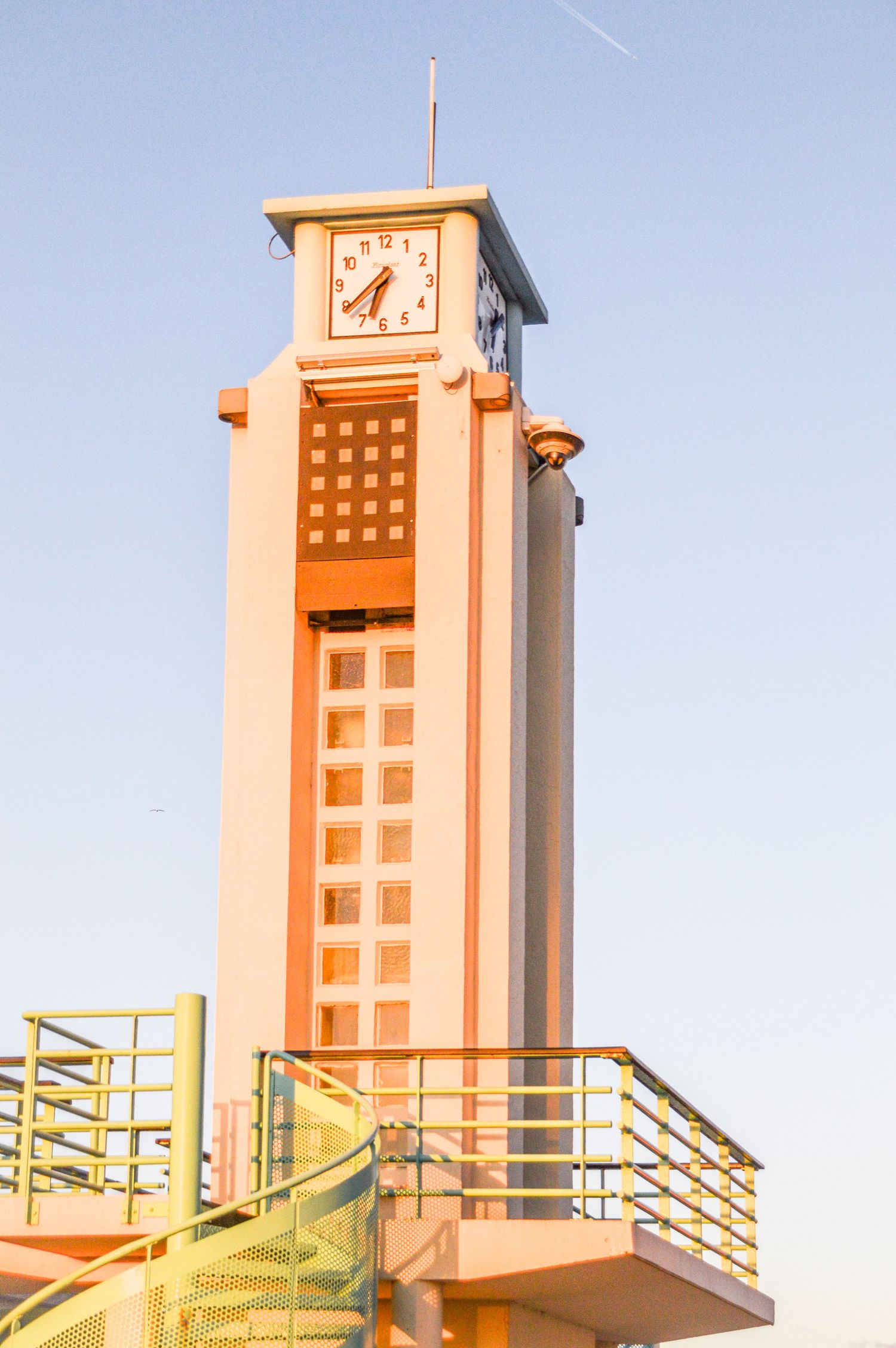 Art deco style observation tower in salmon pink color against blue sky.
