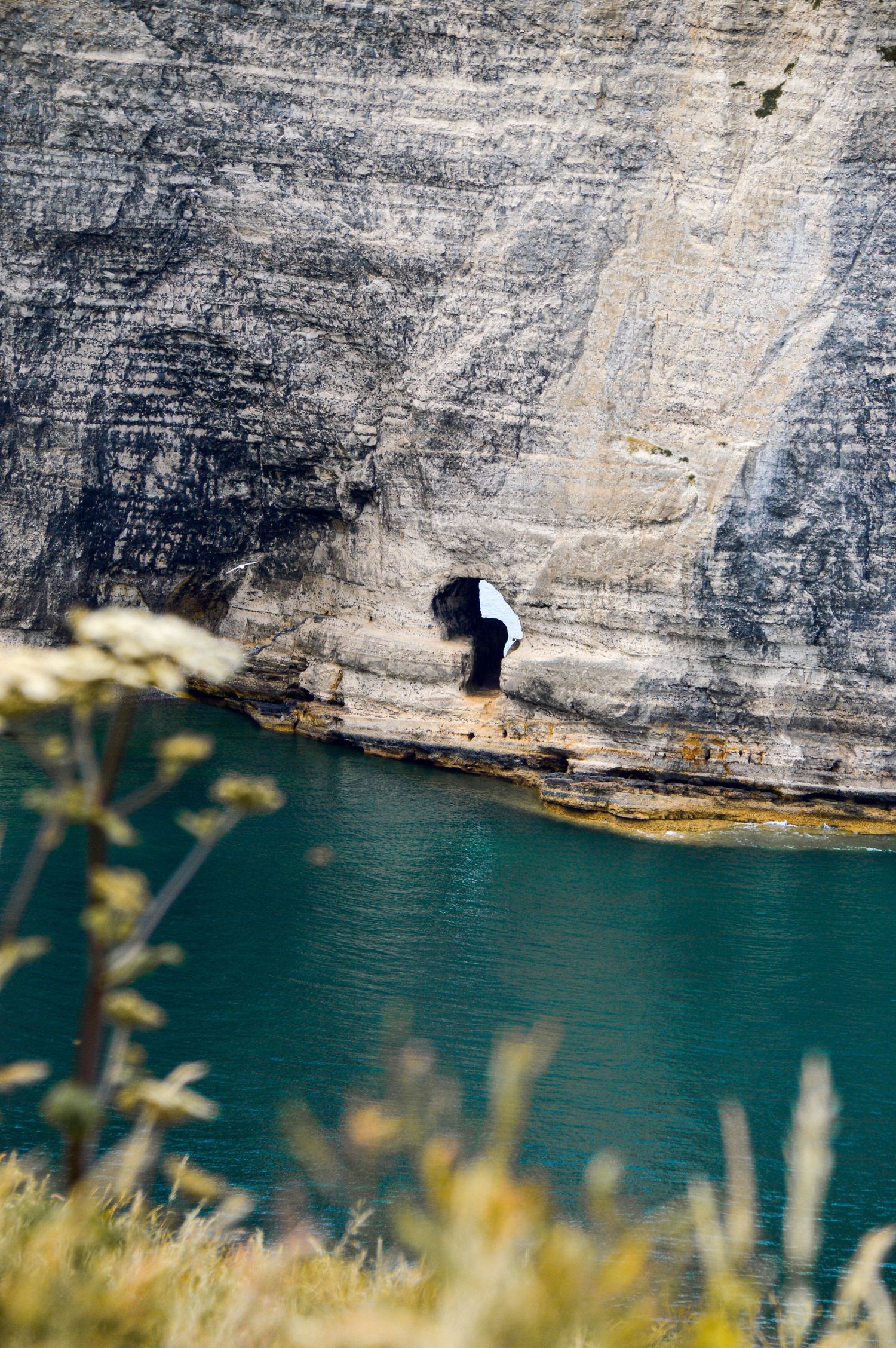 Towering limestone cliffs rise above emerald green waters along a rugged coastline.