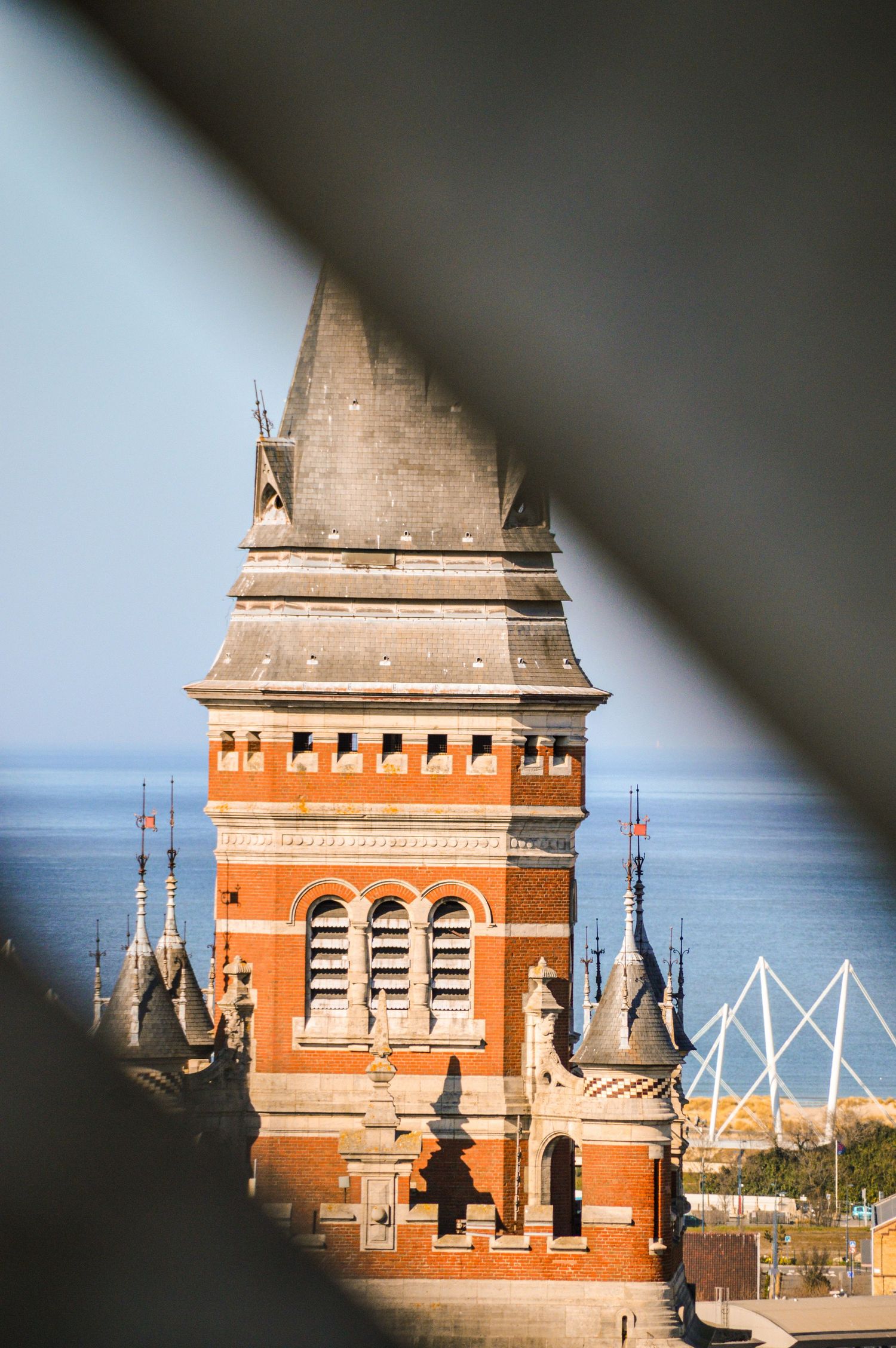 Historic red brick tower with ornate architecture photographed through window frame.