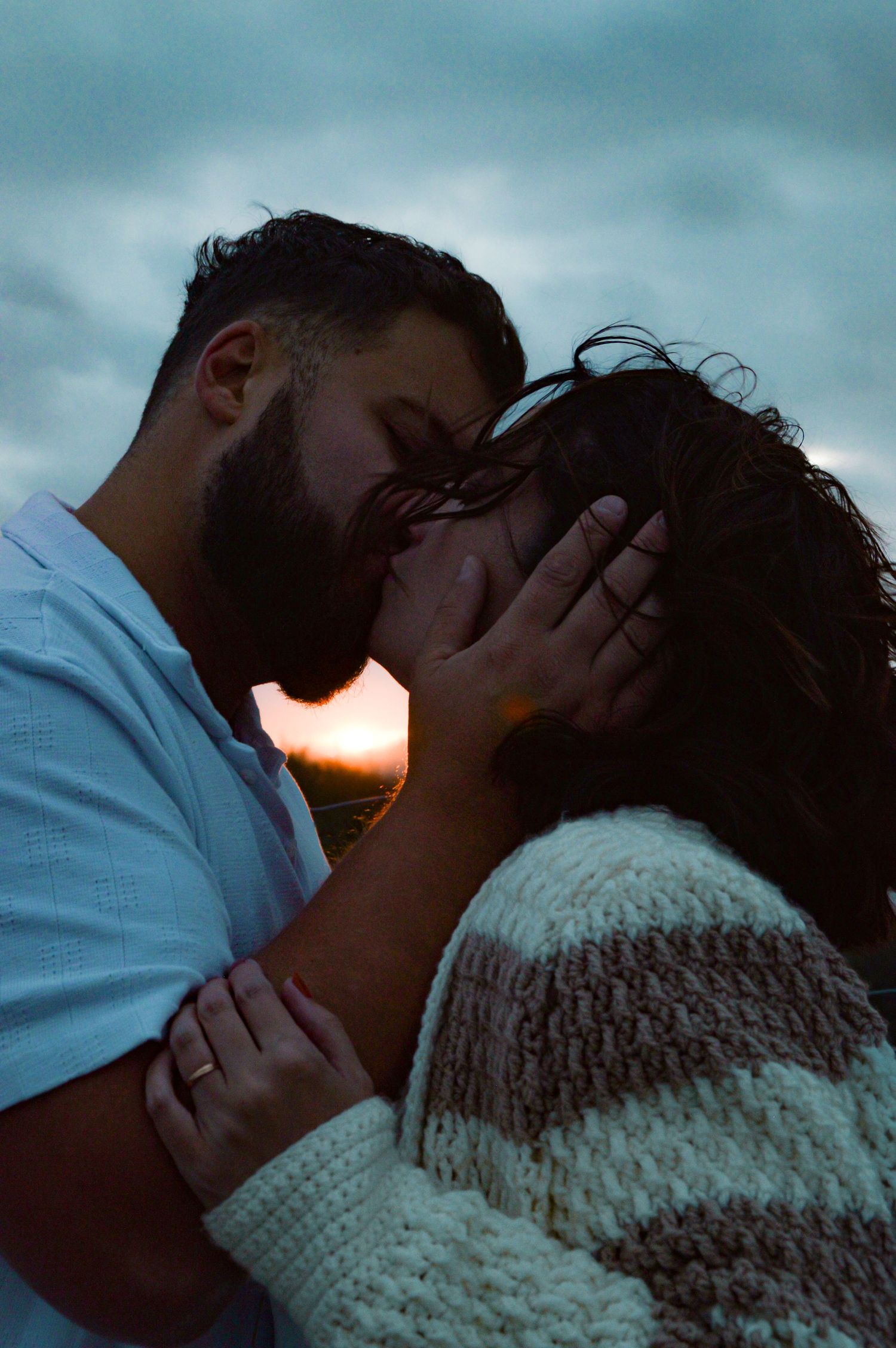 A tender moment between two people against a moody blue sky background.
