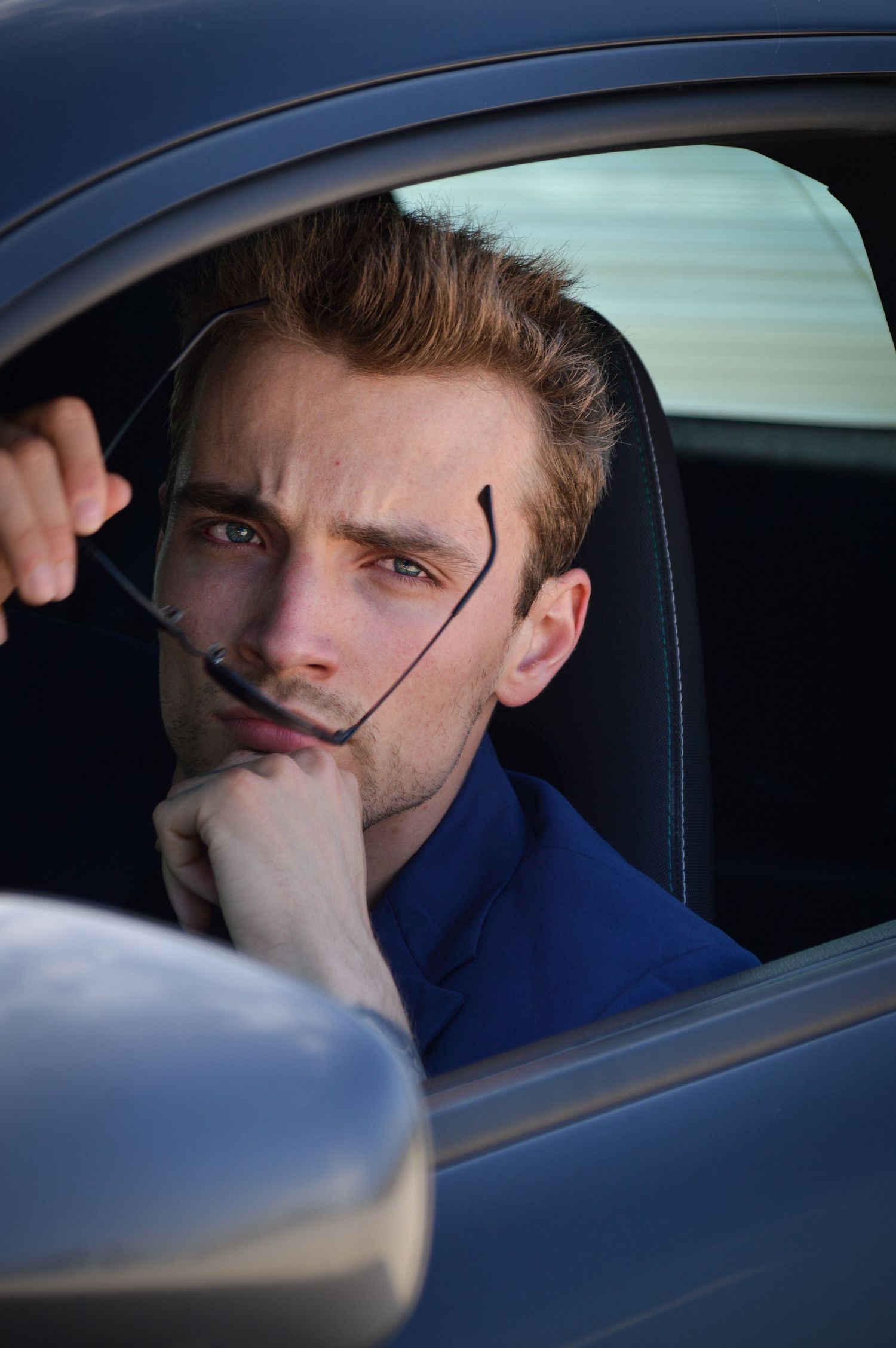 Pensive figure gazing out car window in series of intimate portraits.