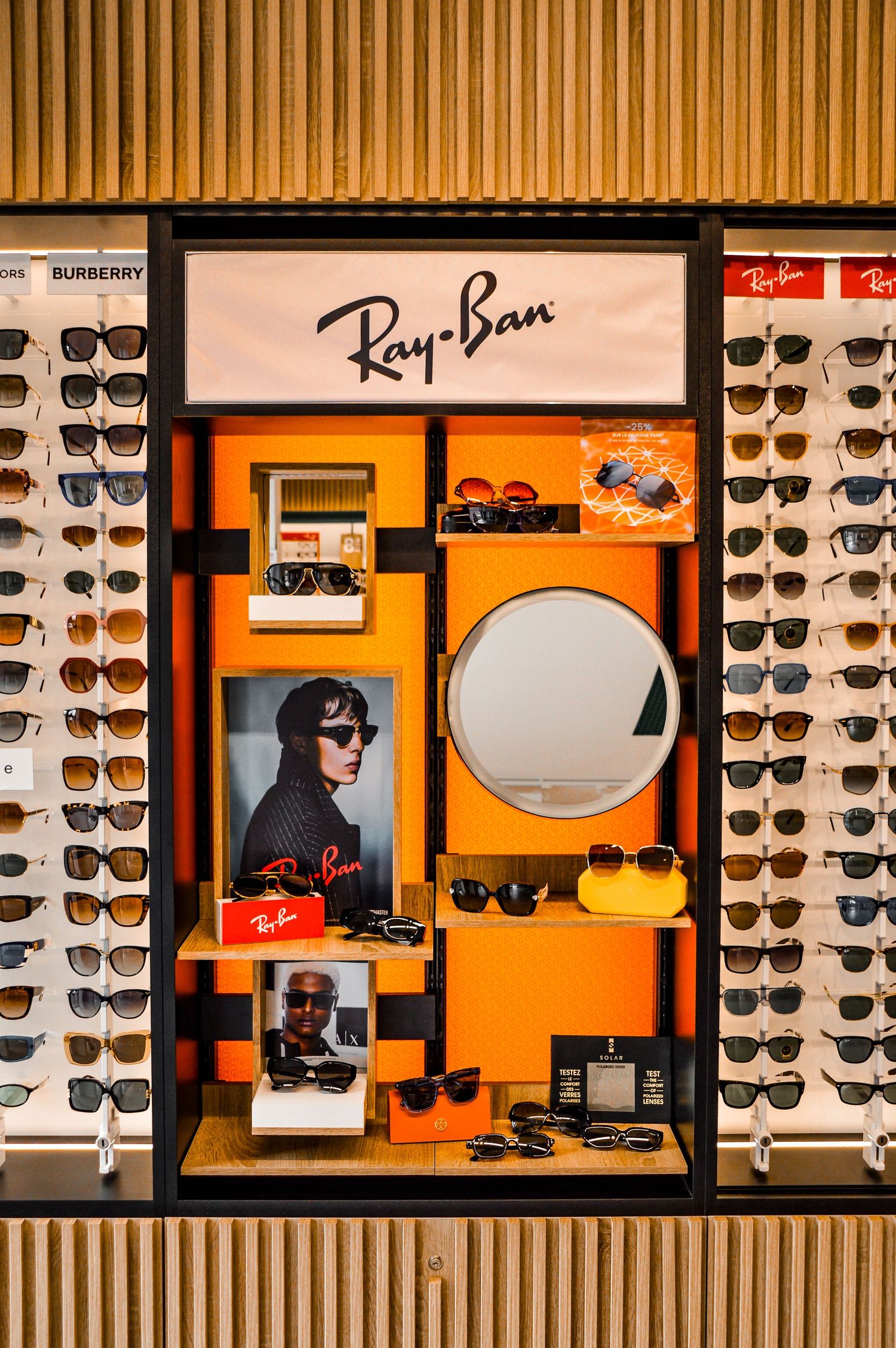 Luxury eyewear retail display featuring Ray-Ban and designer brands in orange and black modular units.
