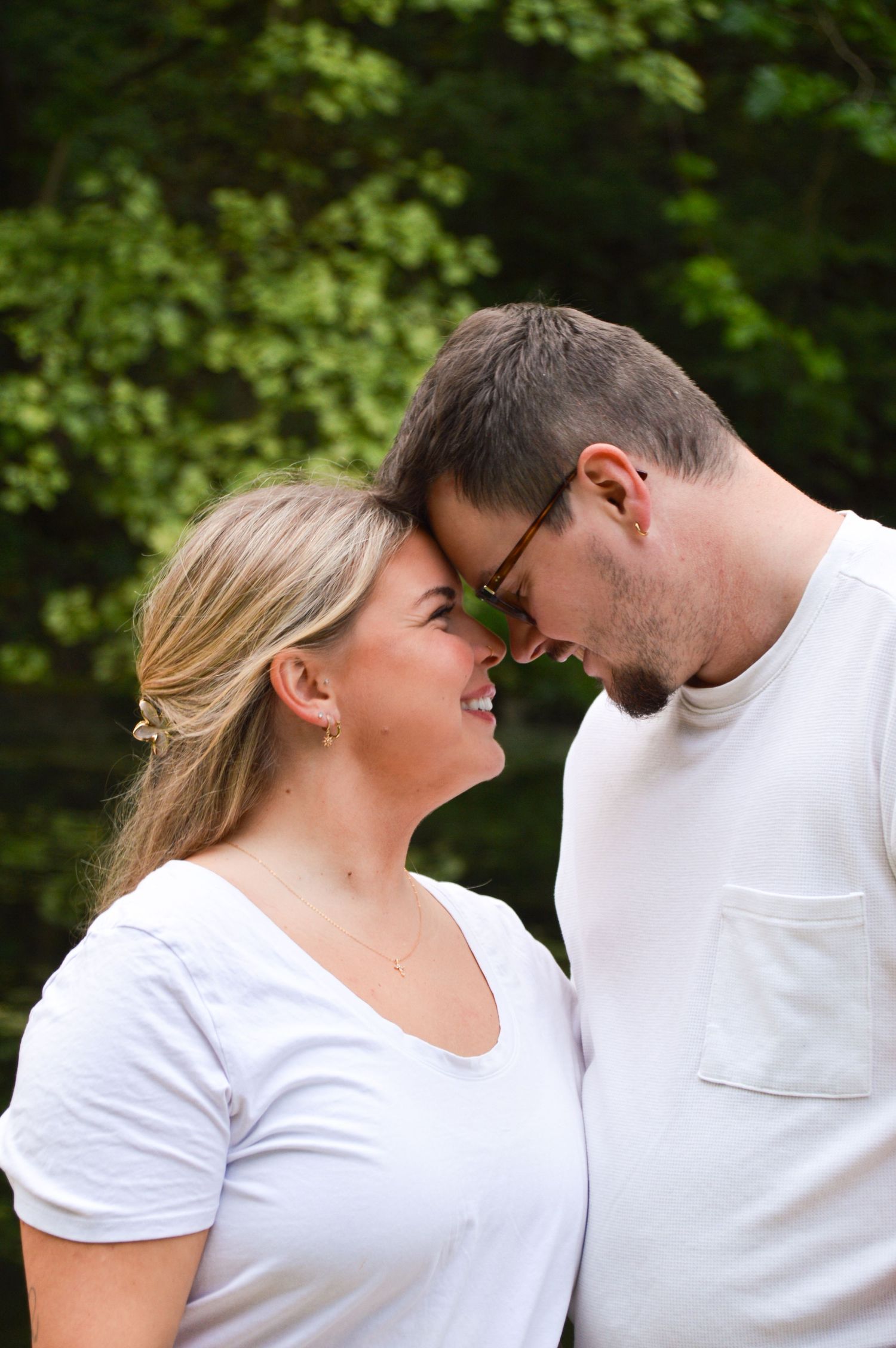 Couple in matching white t-shirts sharing playful moments in a garden setting.