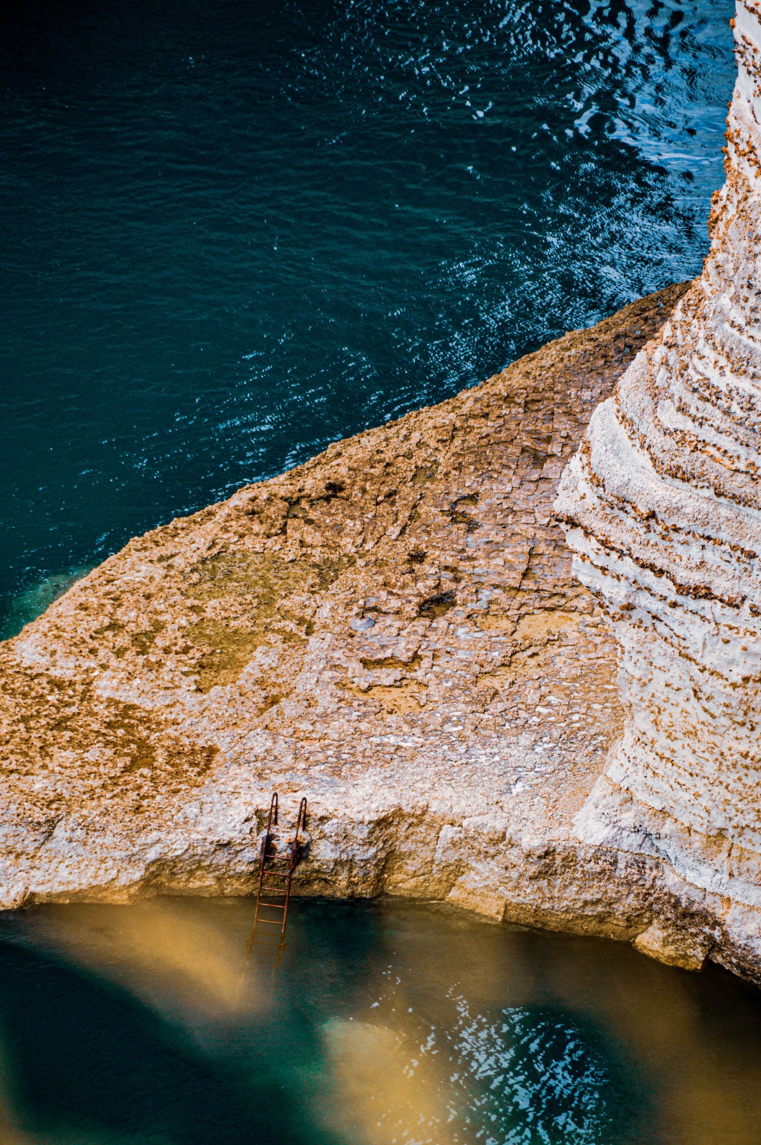 Dramatic white chalk cliffs meeting turquoise waters with sunlit rock formations.