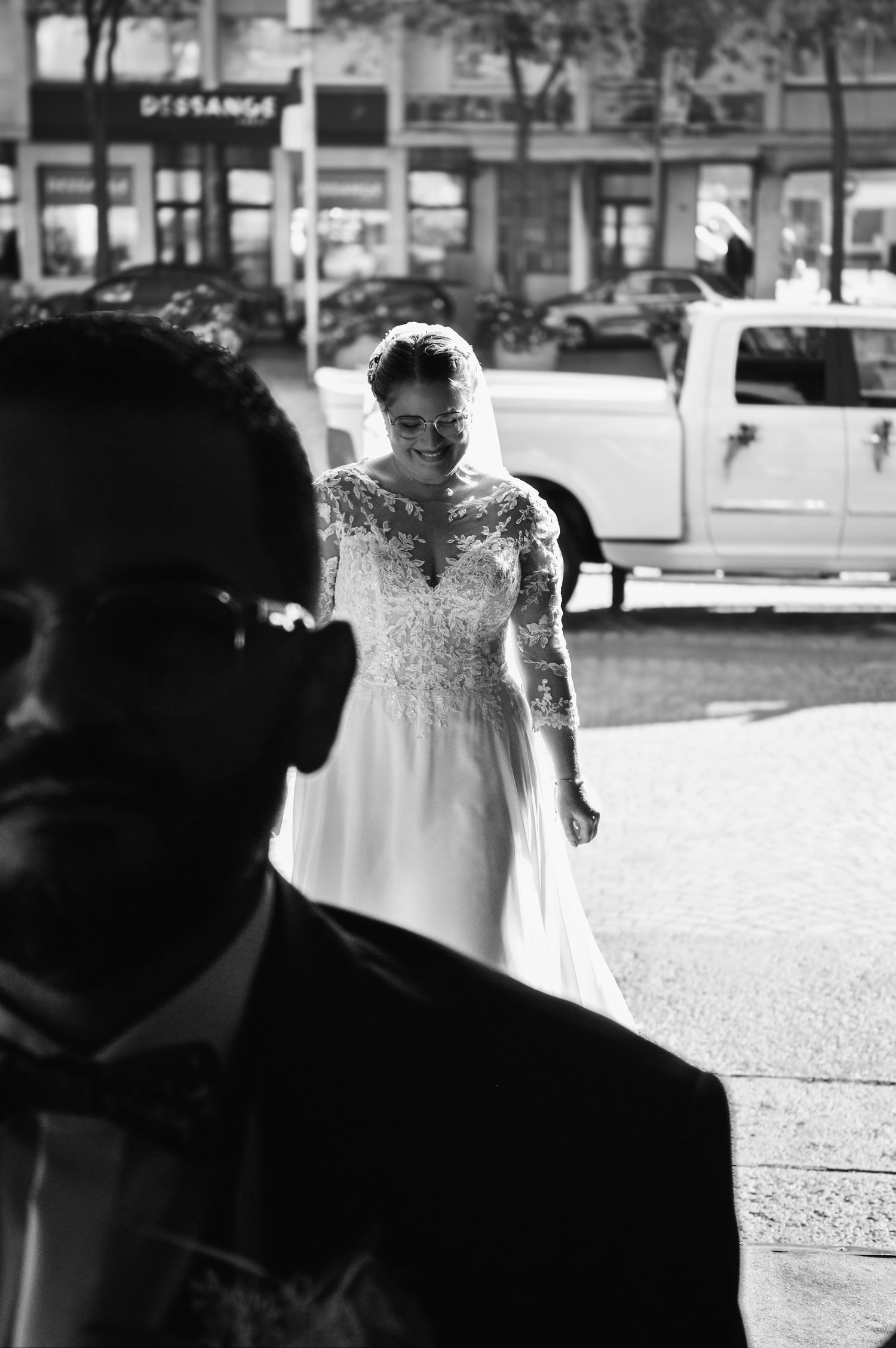 Close-up view of a bride's delicate lace wedding dress detail against a dark background.