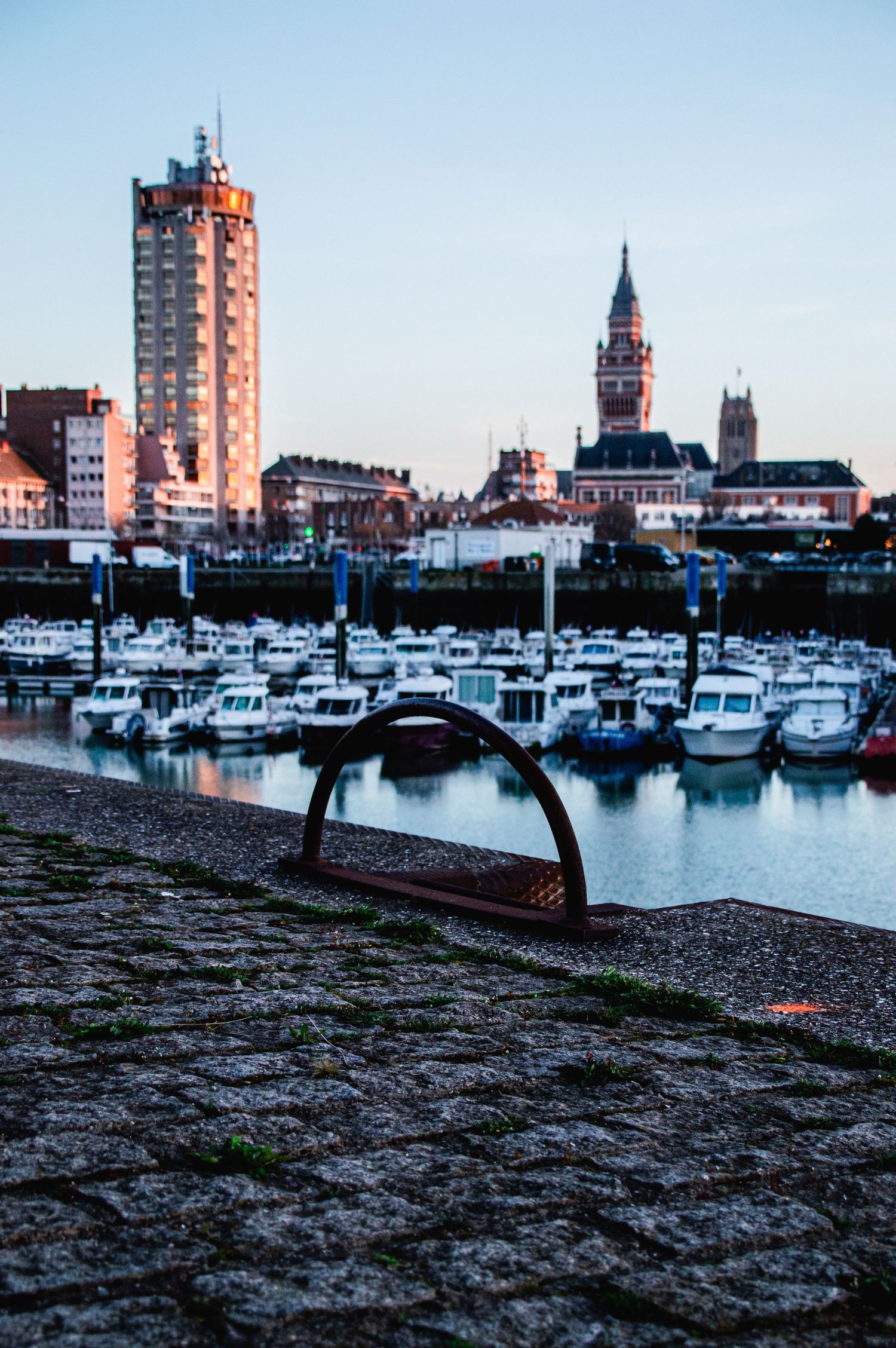 Panoramic view of La Rochelle harbor at dusk with boats moored along the waterfront and historic buildings silhouetted.