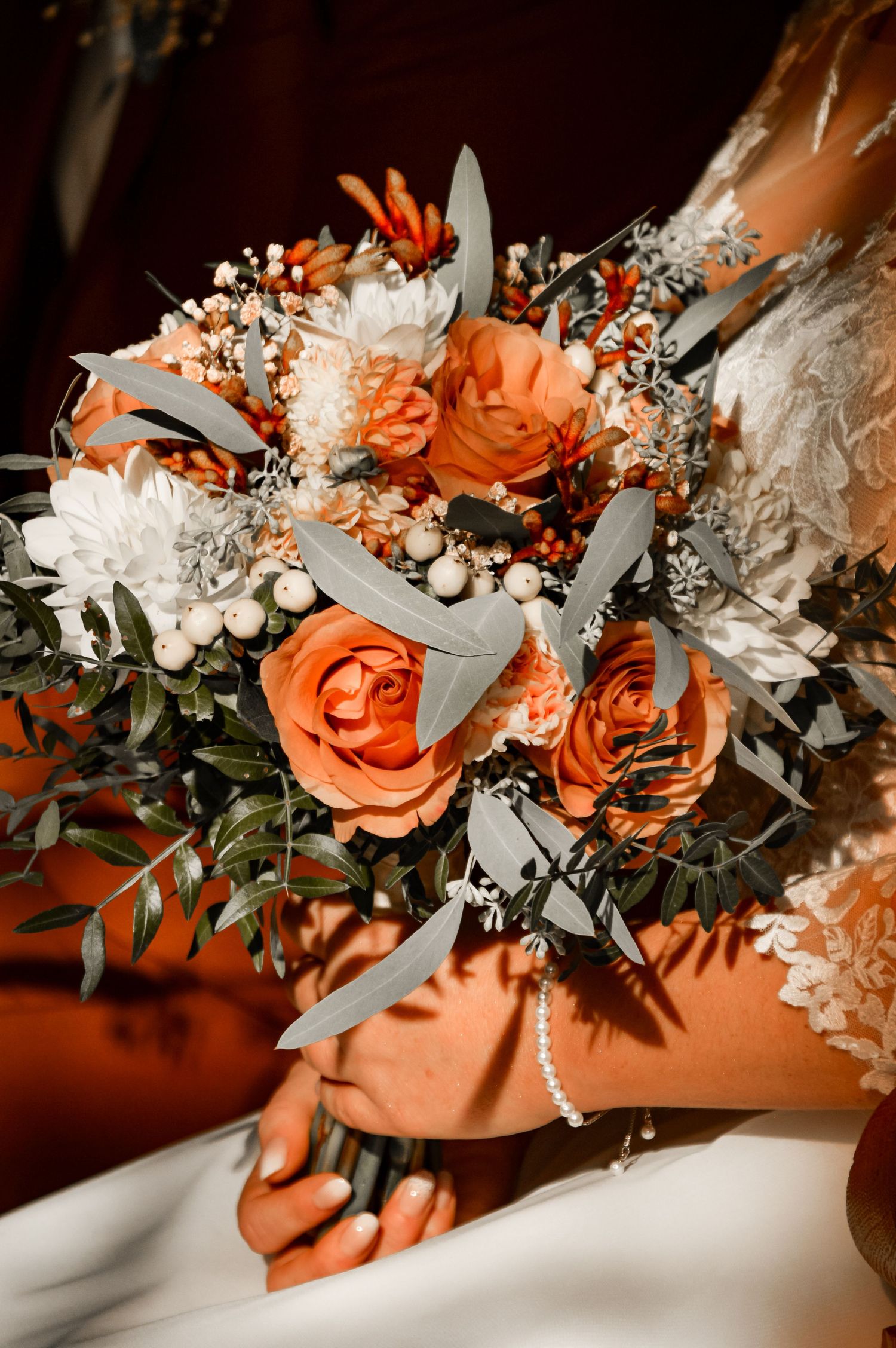 Beautiful wedding bouquet with coral roses, white flowers, and eucalyptus leaves.
