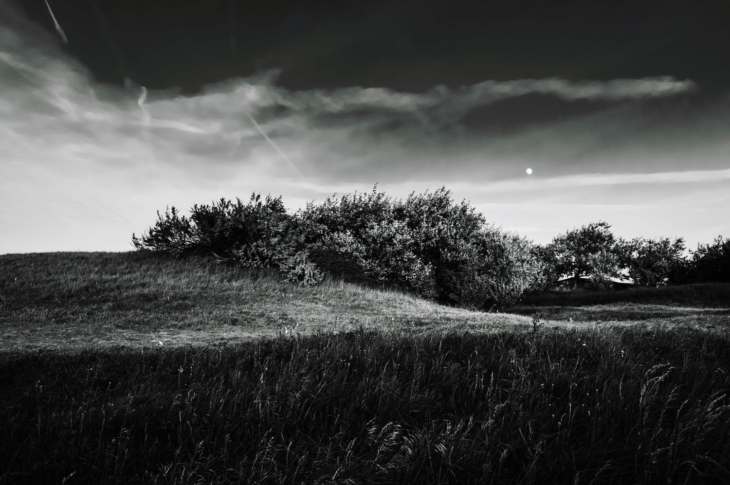 Moody panoramic landscape with rolling hills and dark stormy skies.