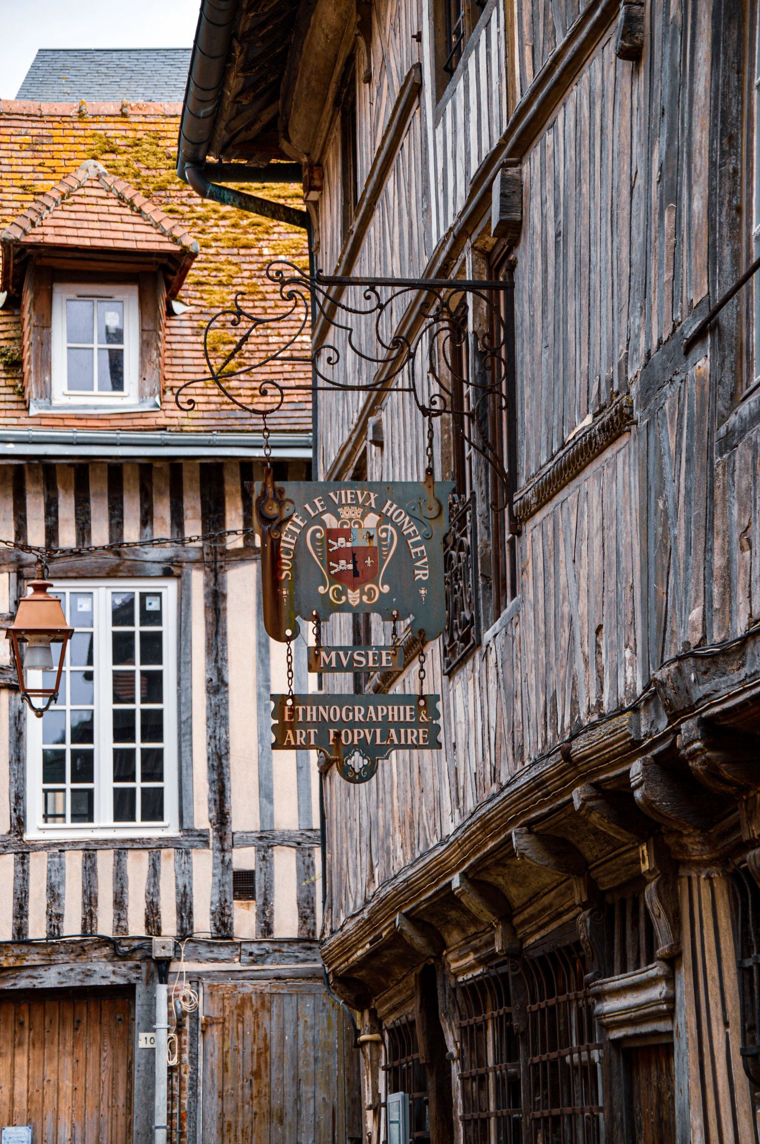 Traditional timber-framed buildings with weathered wood facades line a medieval street.