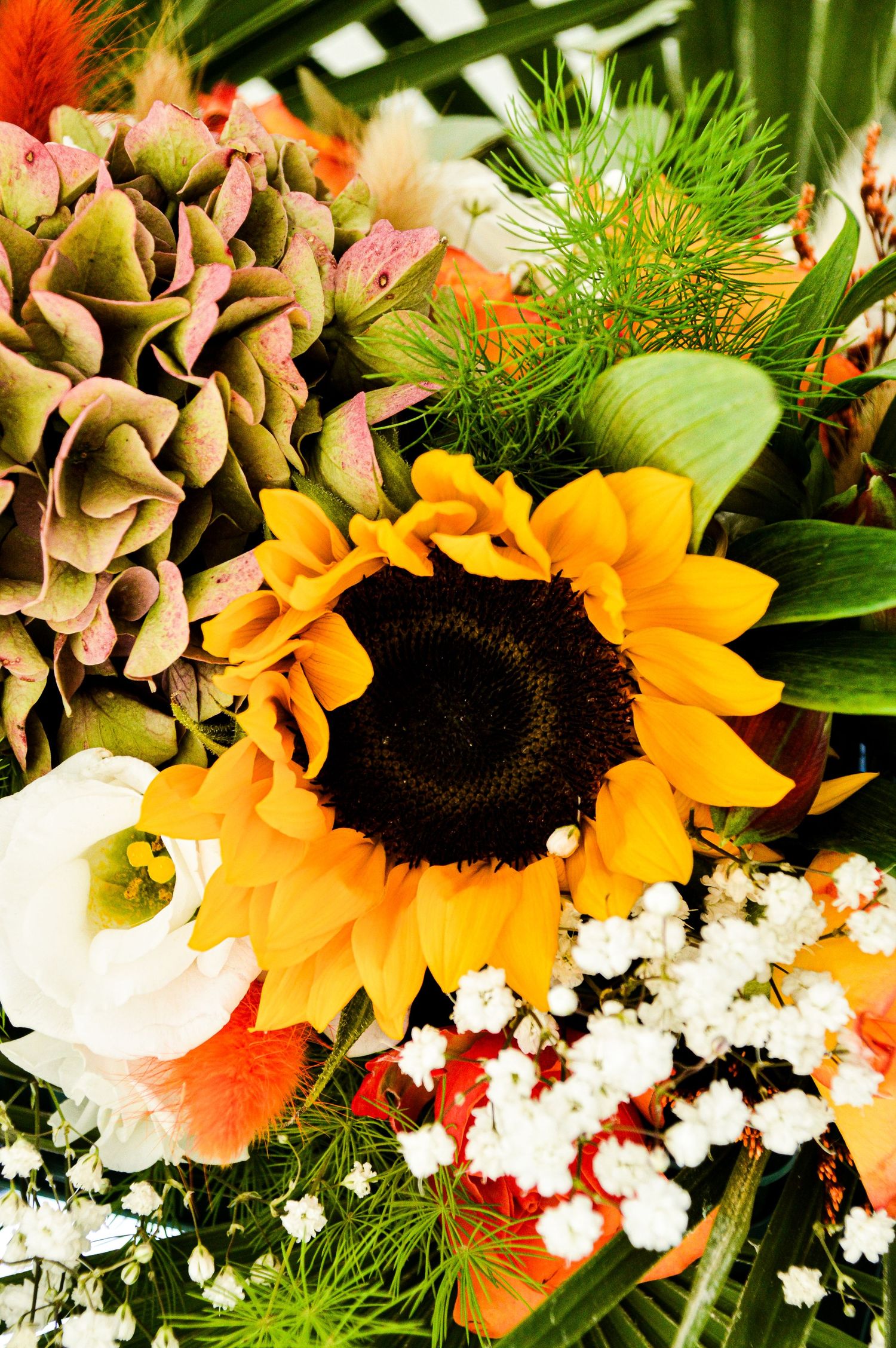 Vibrant arrangement of sunflowers, roses and baby's breath in autumn colors.