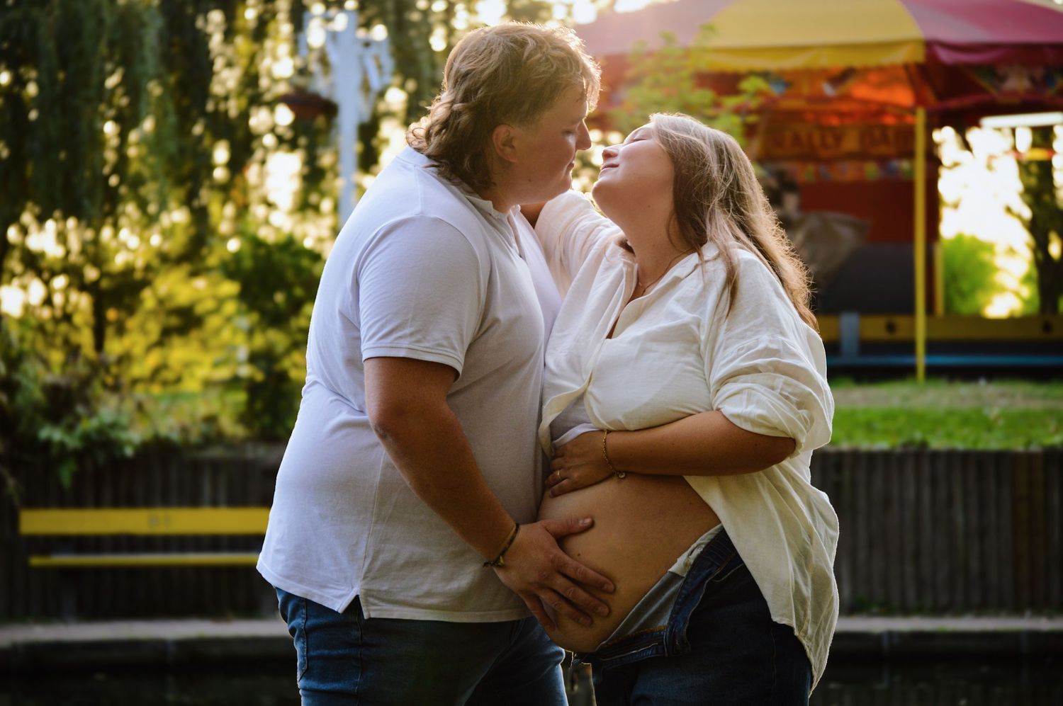 Couple sharing tender moments during a sunset photoshoot in casual white attire.