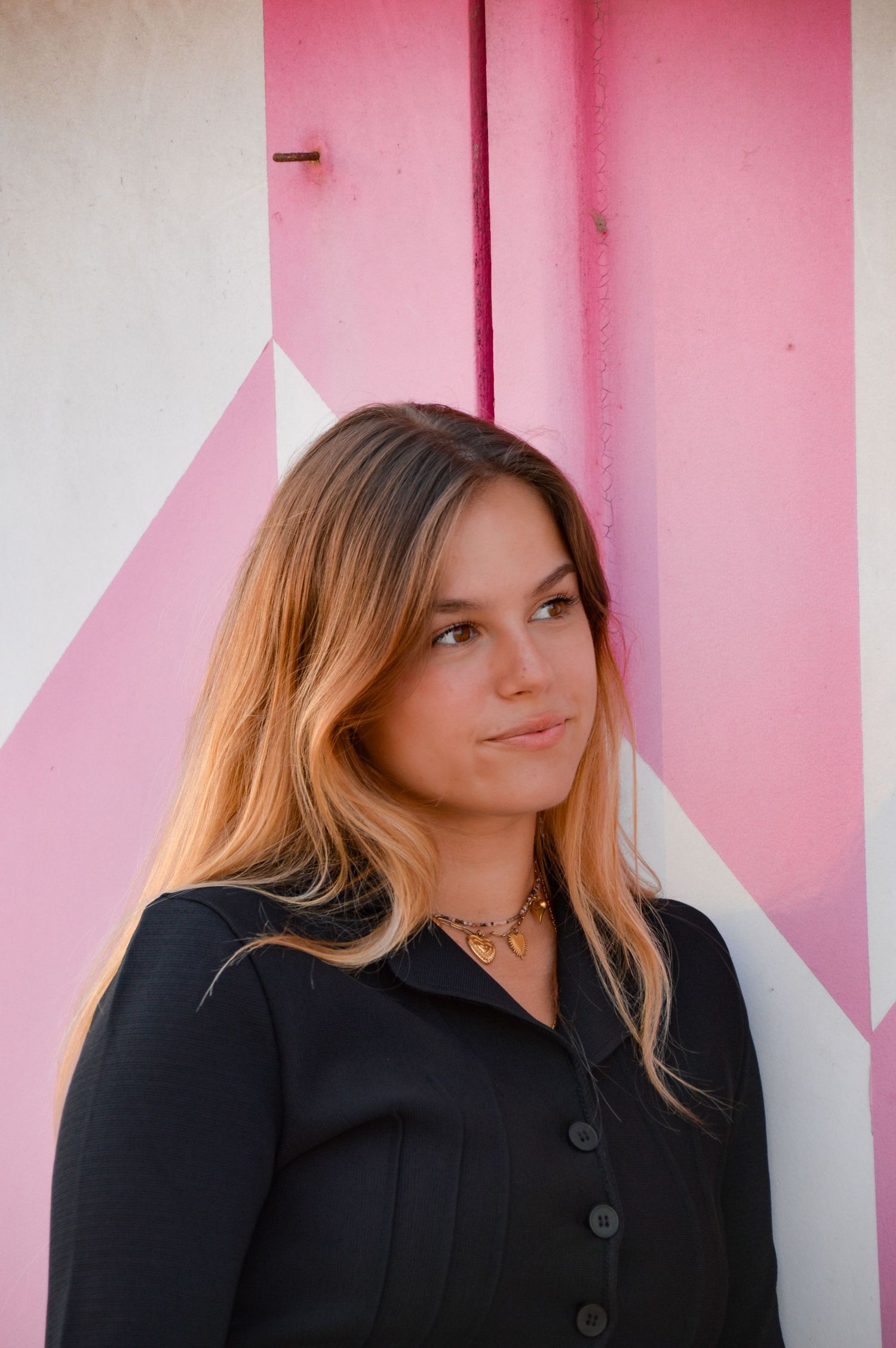Fashion portrait with soft lighting against a pink and white geometric wall background.