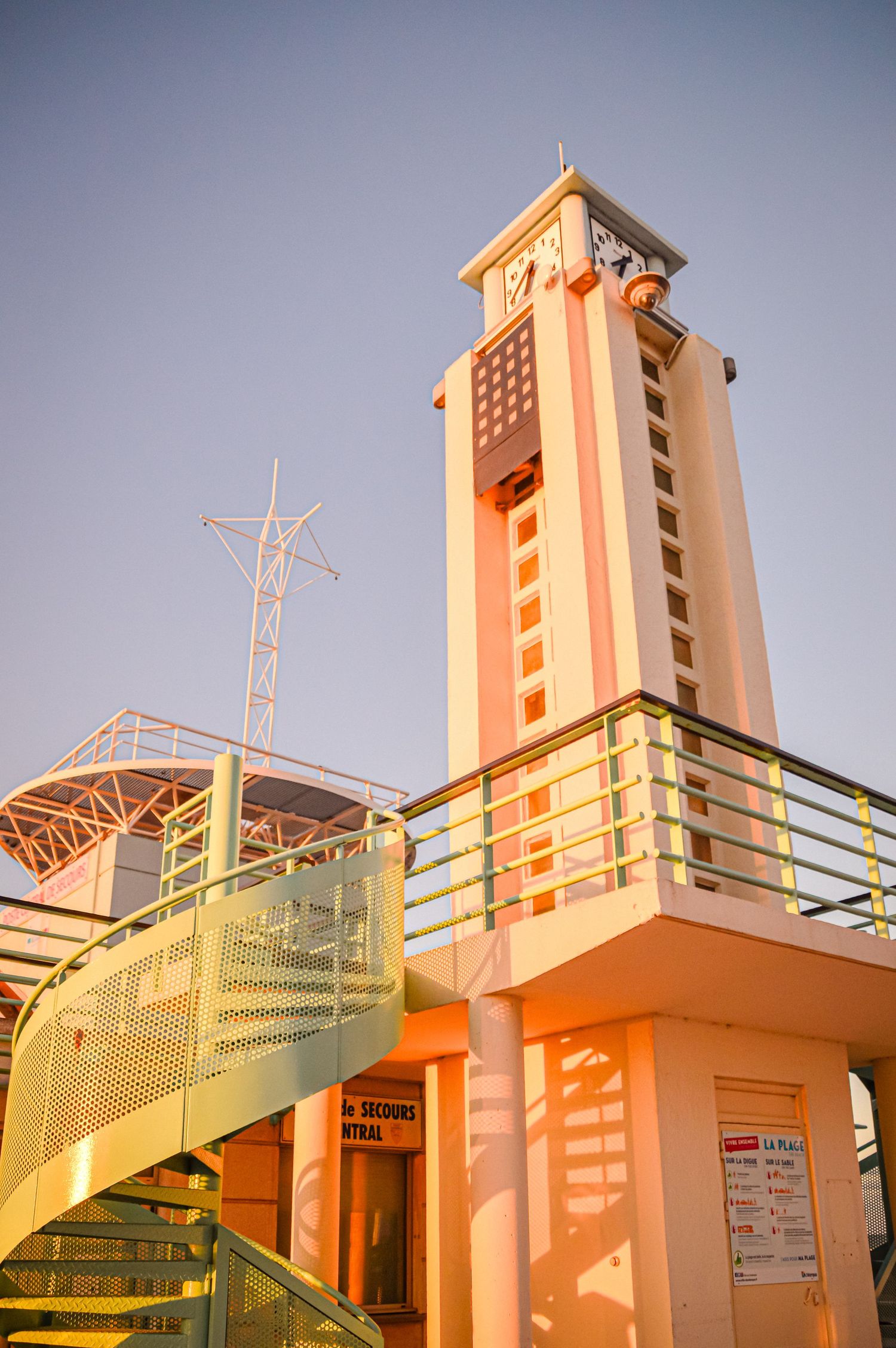 Orange and white lifeguard tower architecture against blue sky.