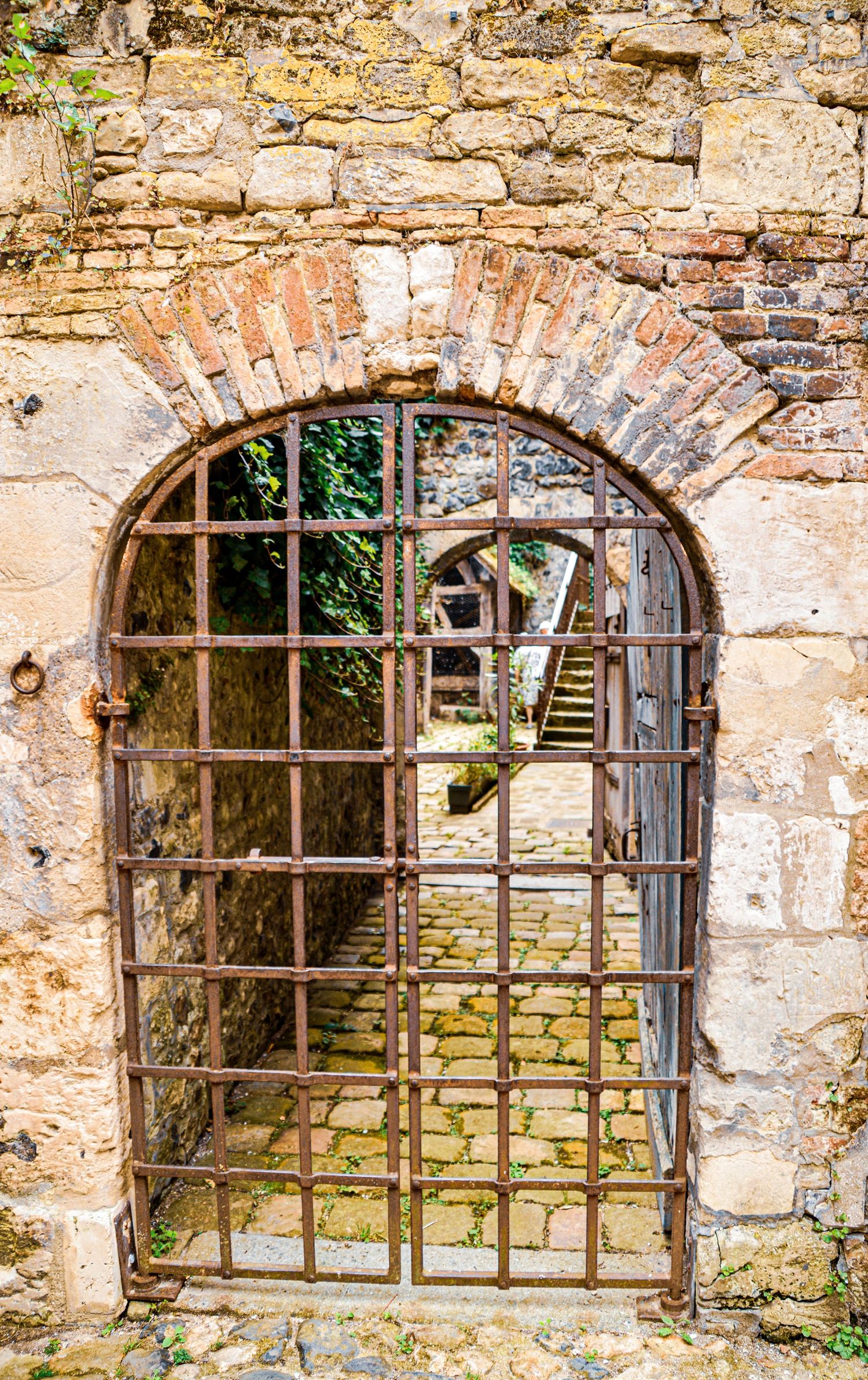 Ancient stone wall with arched windows showing rustic iron bars and weathered masonry.