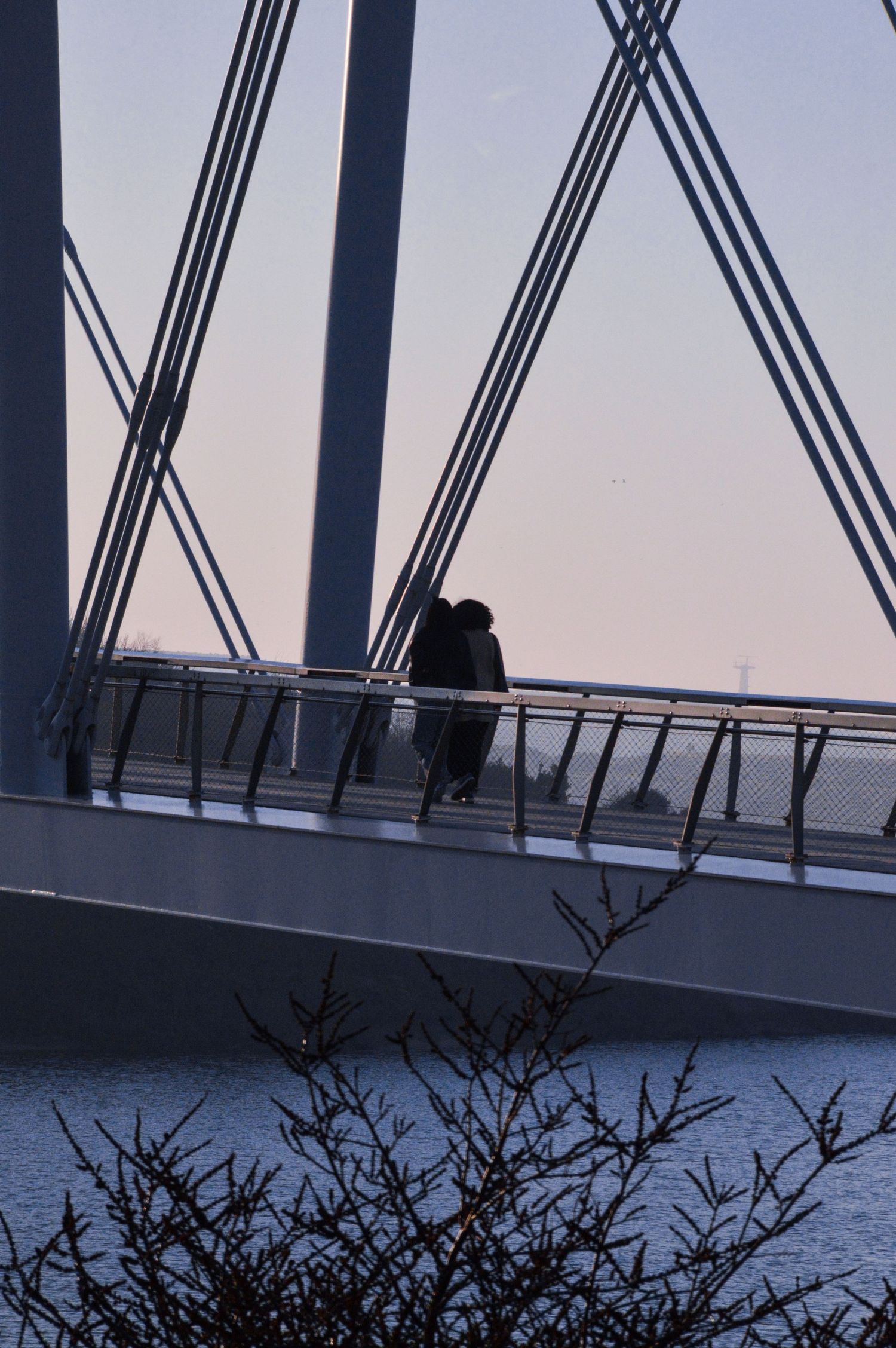 Silhouette sur un pont moderne avec des poutres de soutien en acier géométriques au crépuscule.