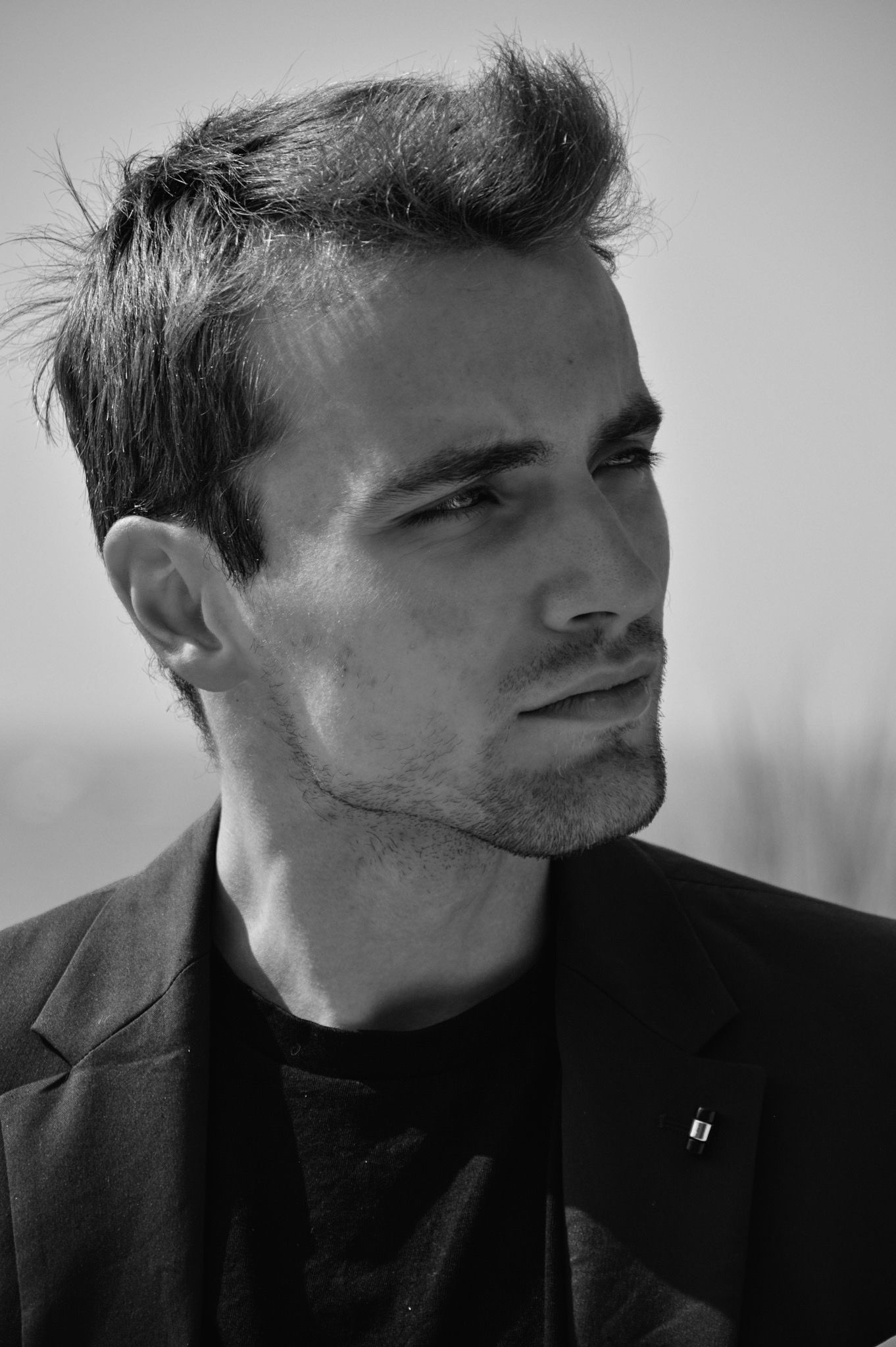 Dramatic black and white close-up portrait in dark clothing.