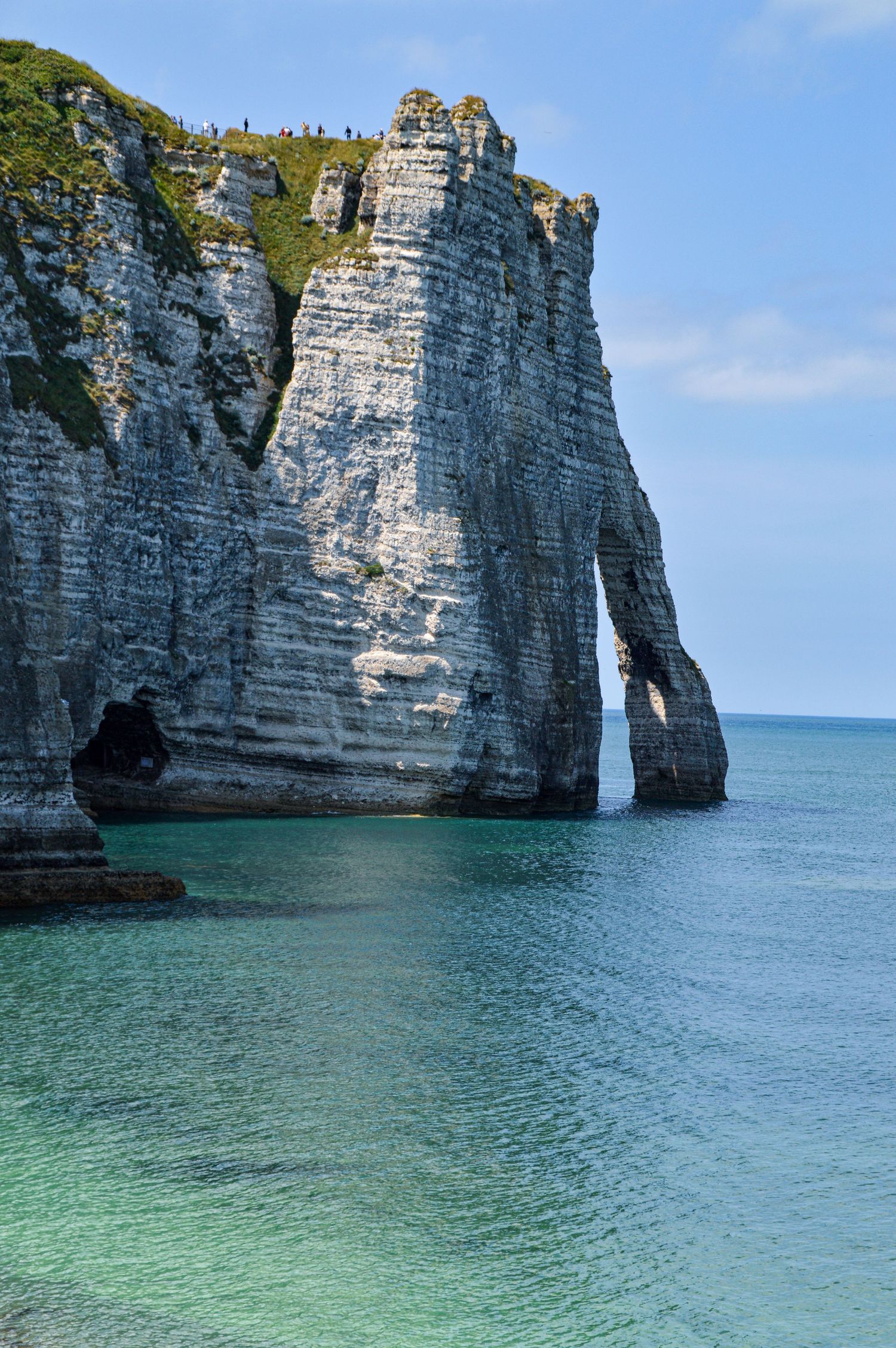 Stunning limestone cliffs and natural arch formations along turquoise coastline.