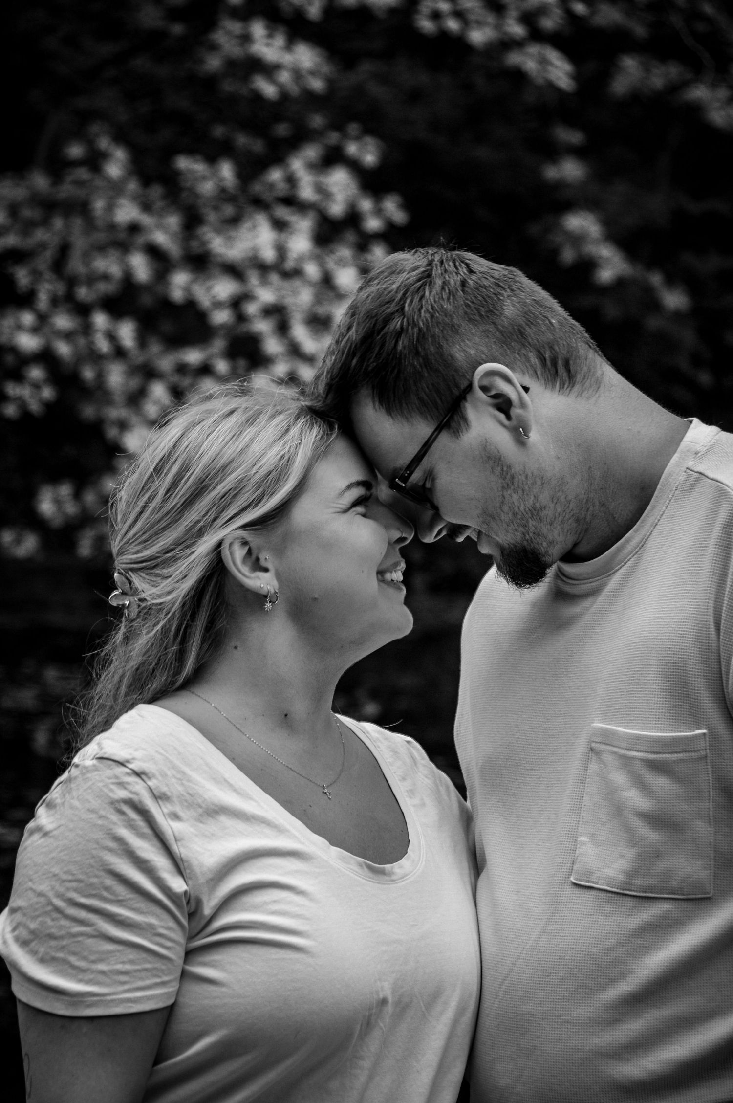 Black and white photo sequence of a couple leaning in close together against natural backdrop.