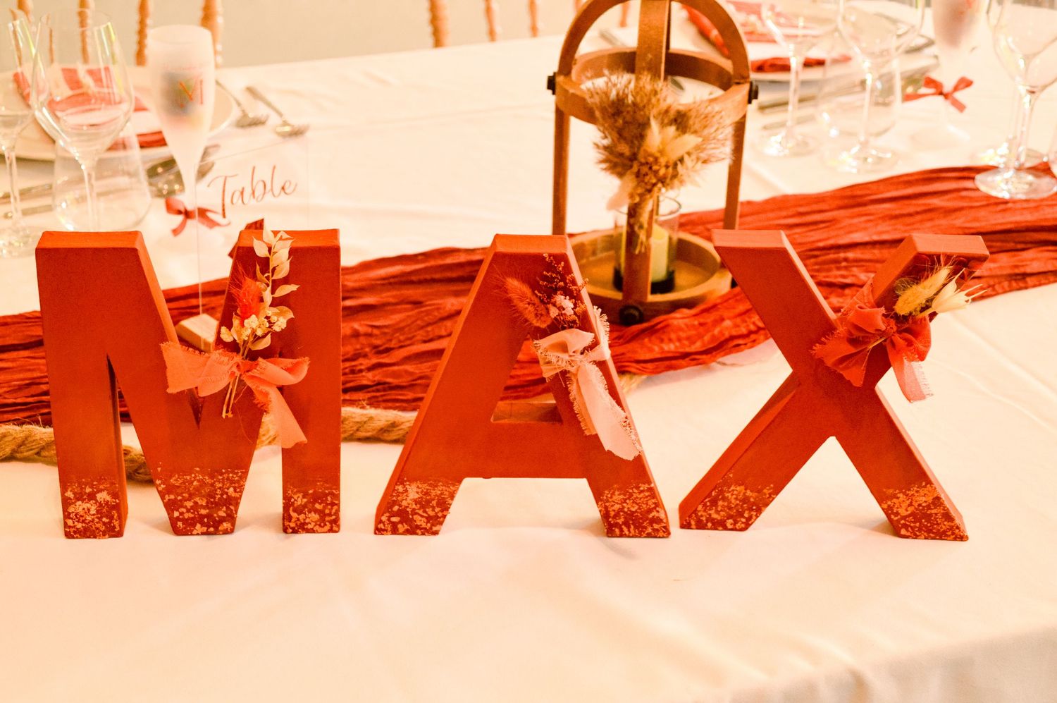 Red decorative letters spelling 'MAX' with ornate details on white tablecloth.