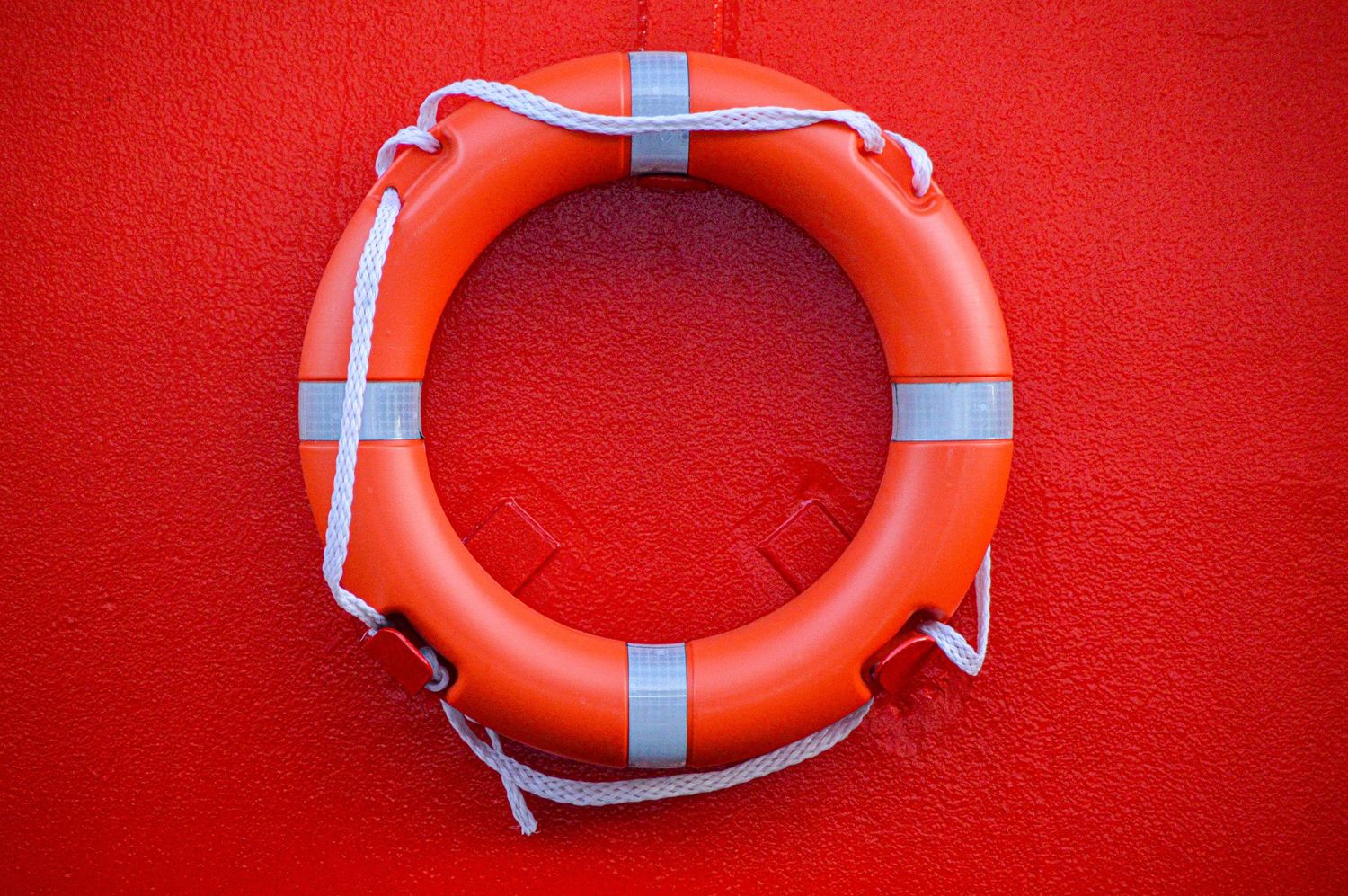 Orange life preservers mounted on red wall in sequential arrangement.
