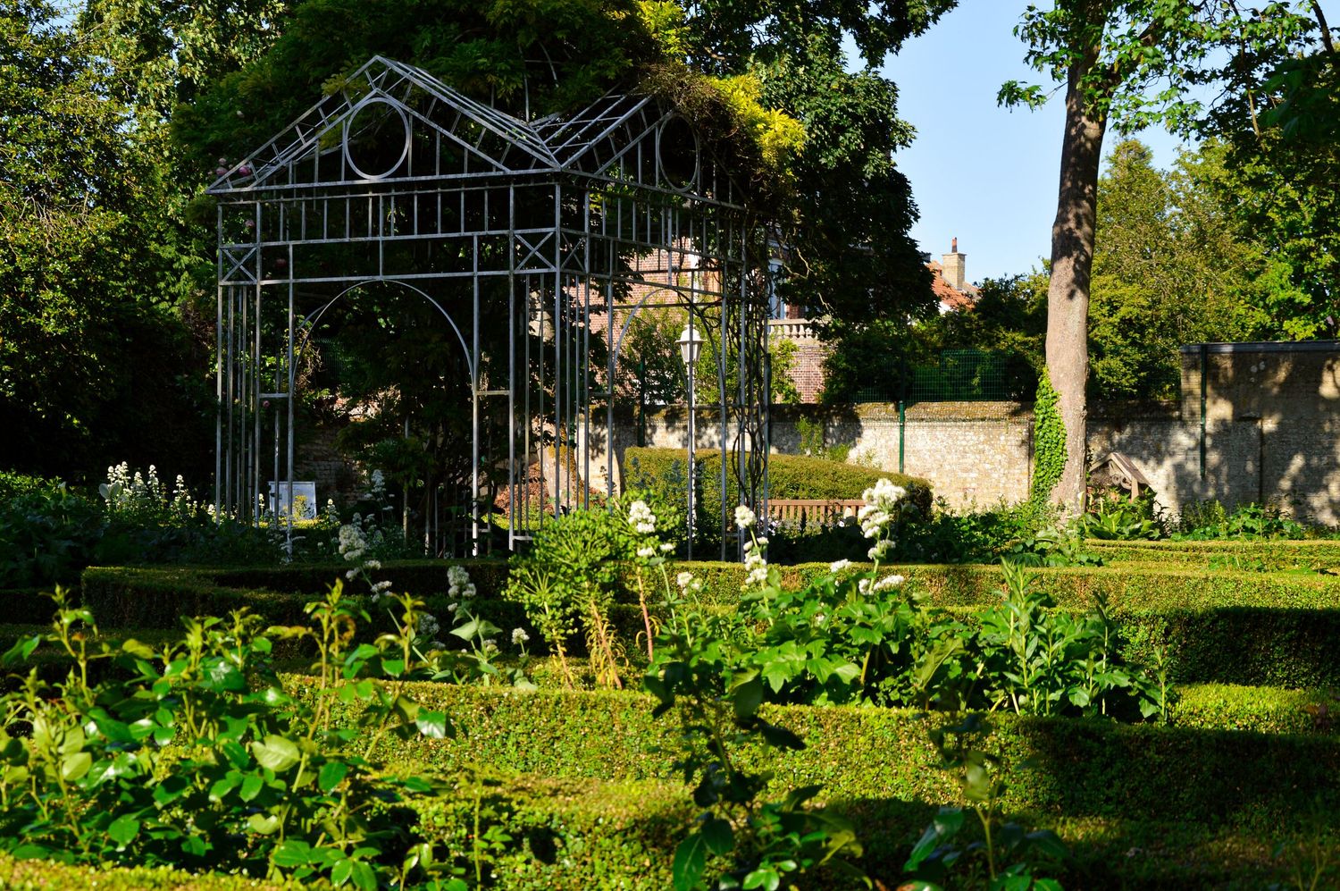 A metal garden archway structure spans across a green landscaped area.