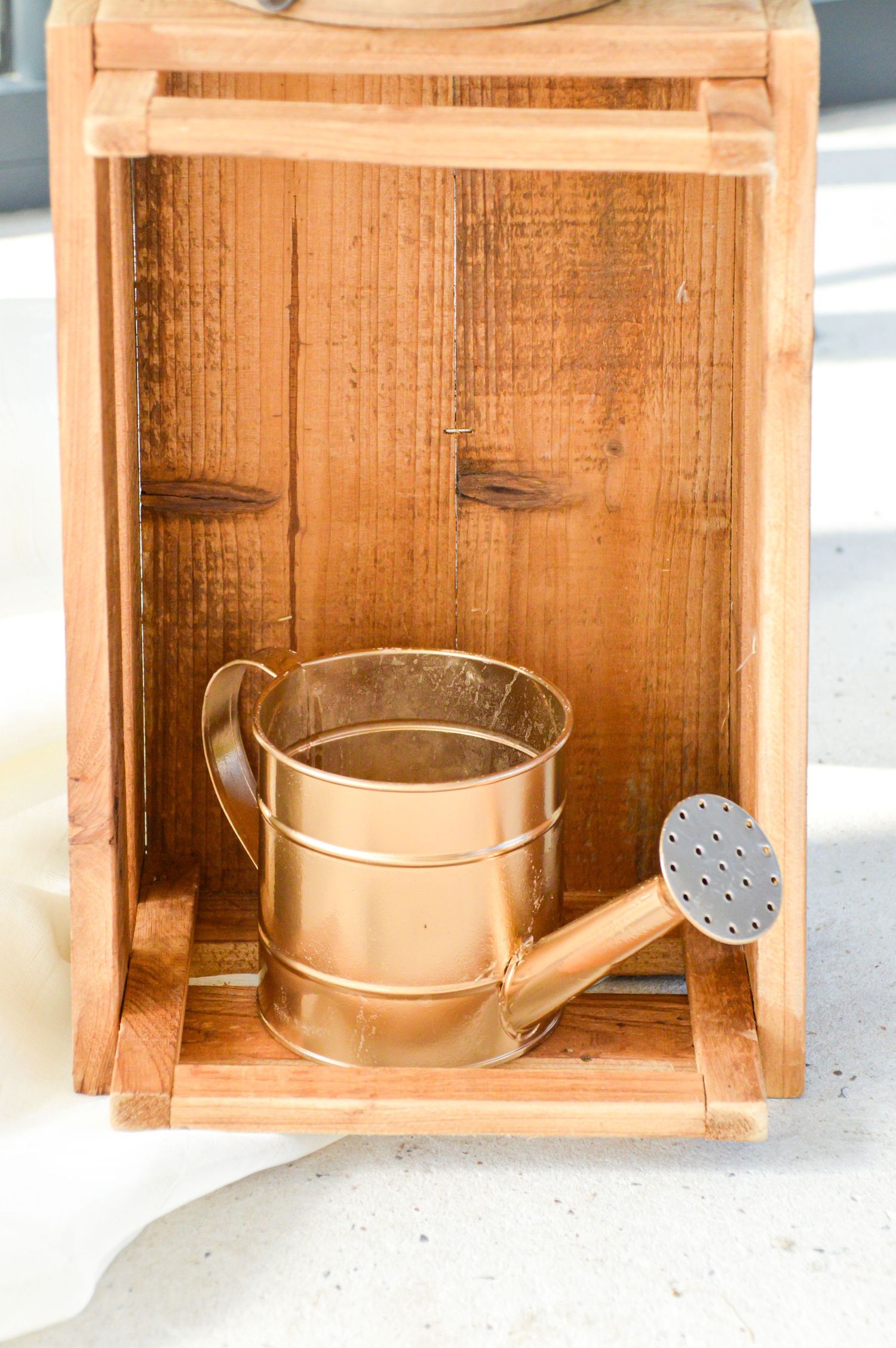 Wooden crates with copper watering cans arranged in sequence.