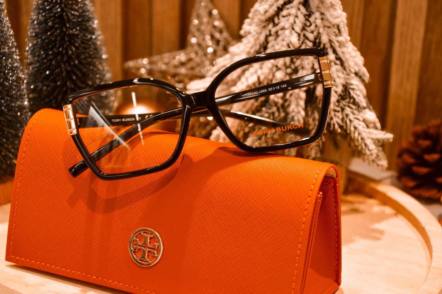Designer eyewear showcased against orange background with seasonal decorations.
