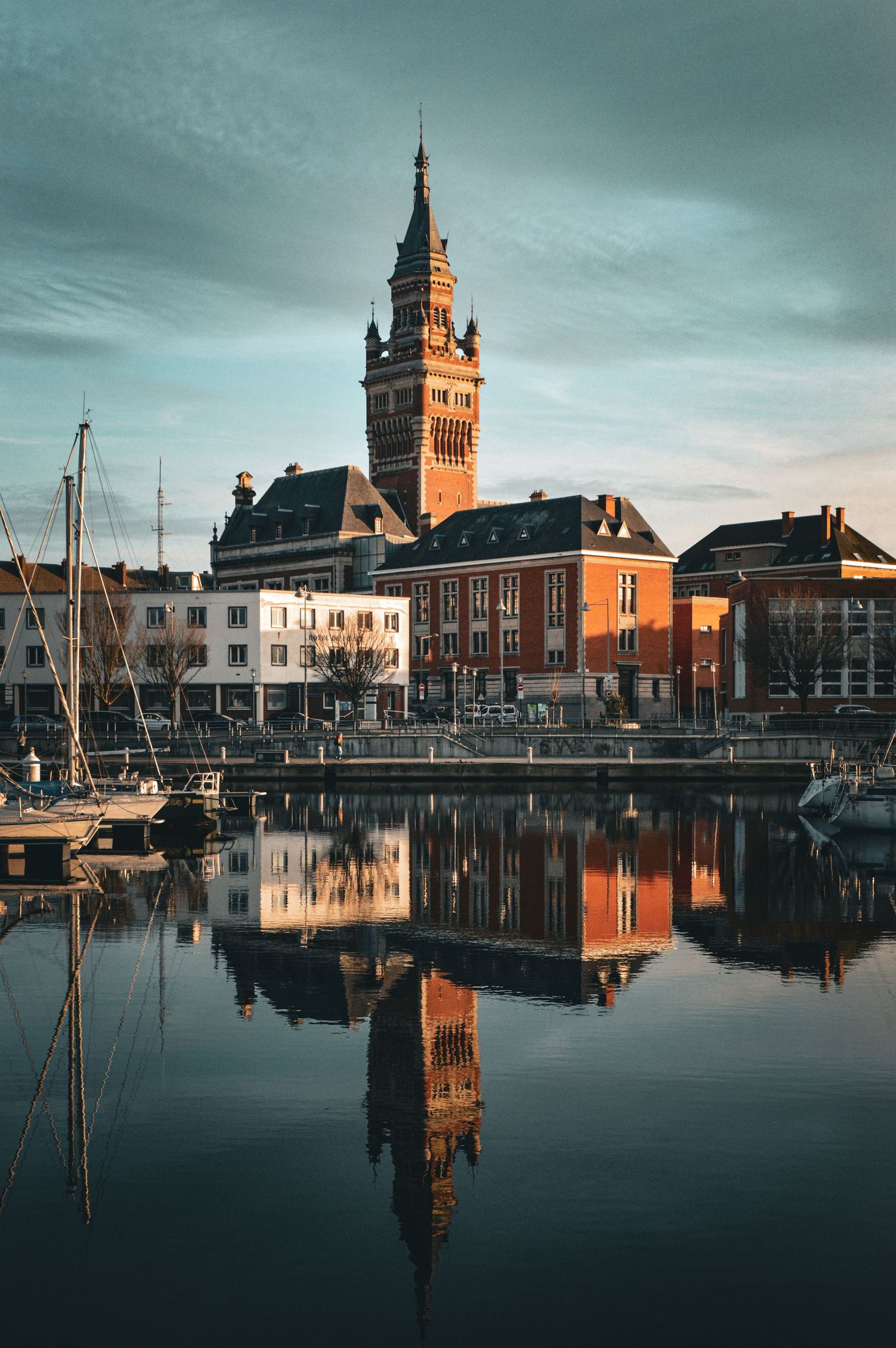 Historic waterfront buildings and clock tower reflecting in calm harbor waters at dusk.