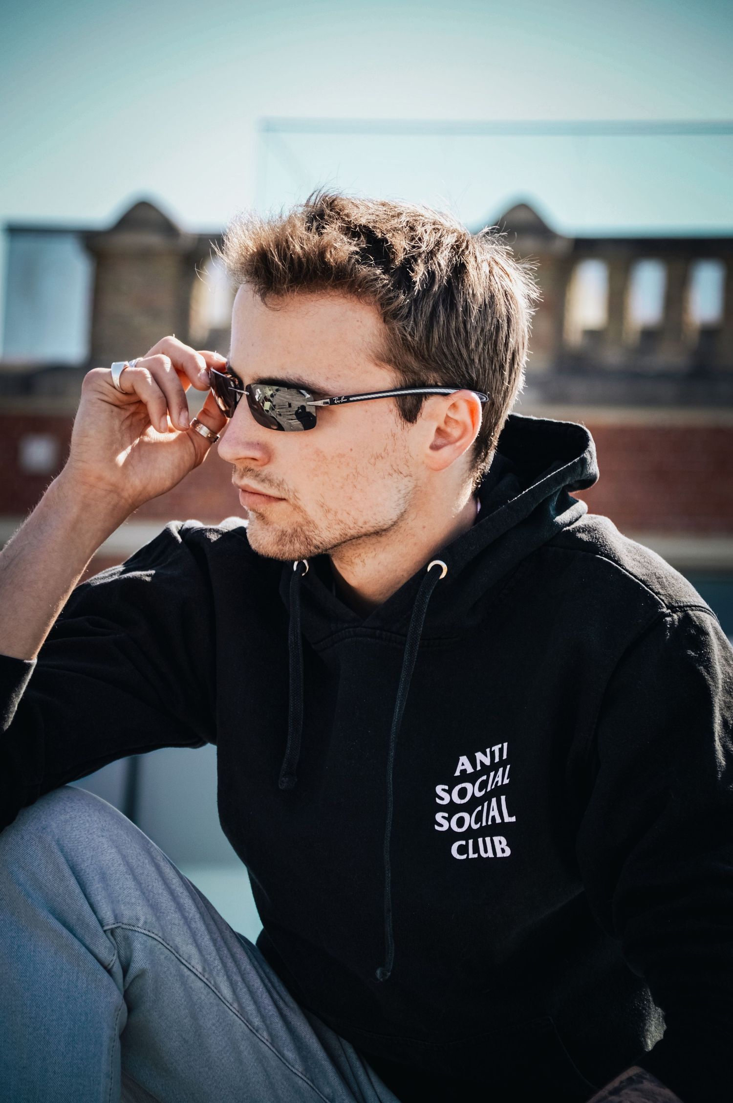 A person wearing a black hoodie with sunglasses in an urban setting.