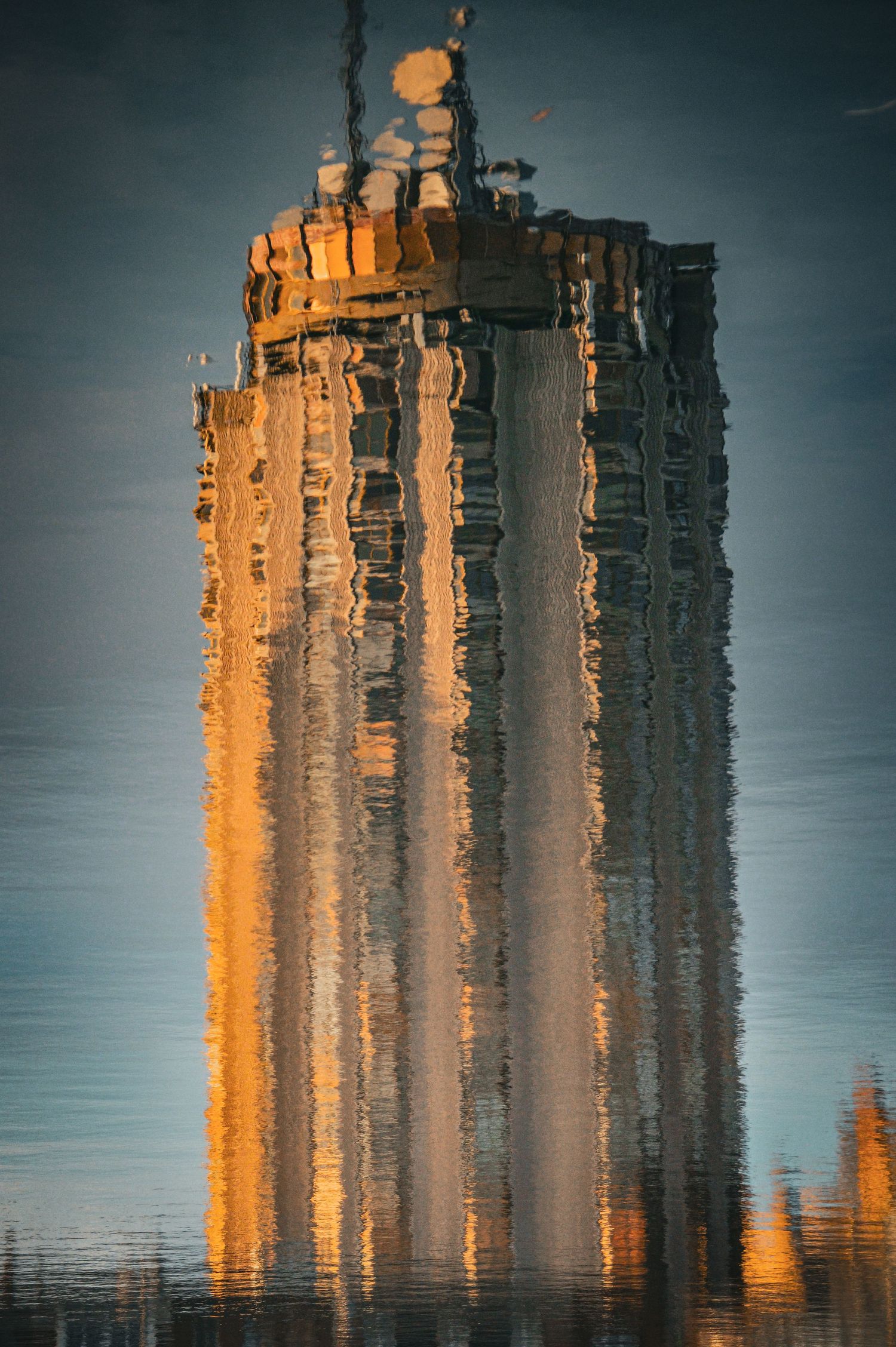 Golden sunlit buildings reflecting in still water creating mirror-like symmetry.