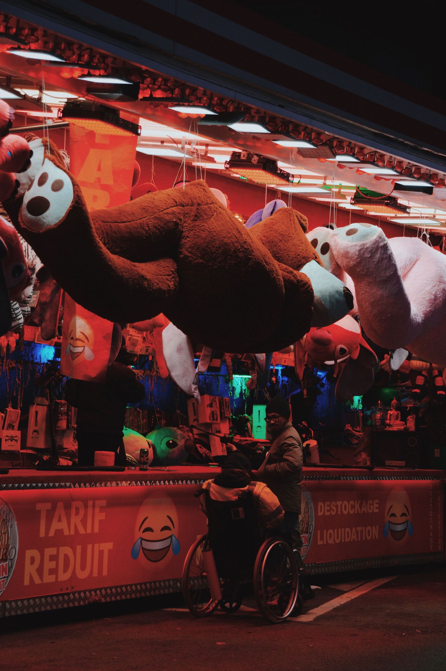 Carnival game booth displaying large plush panda prizes under red lighting.