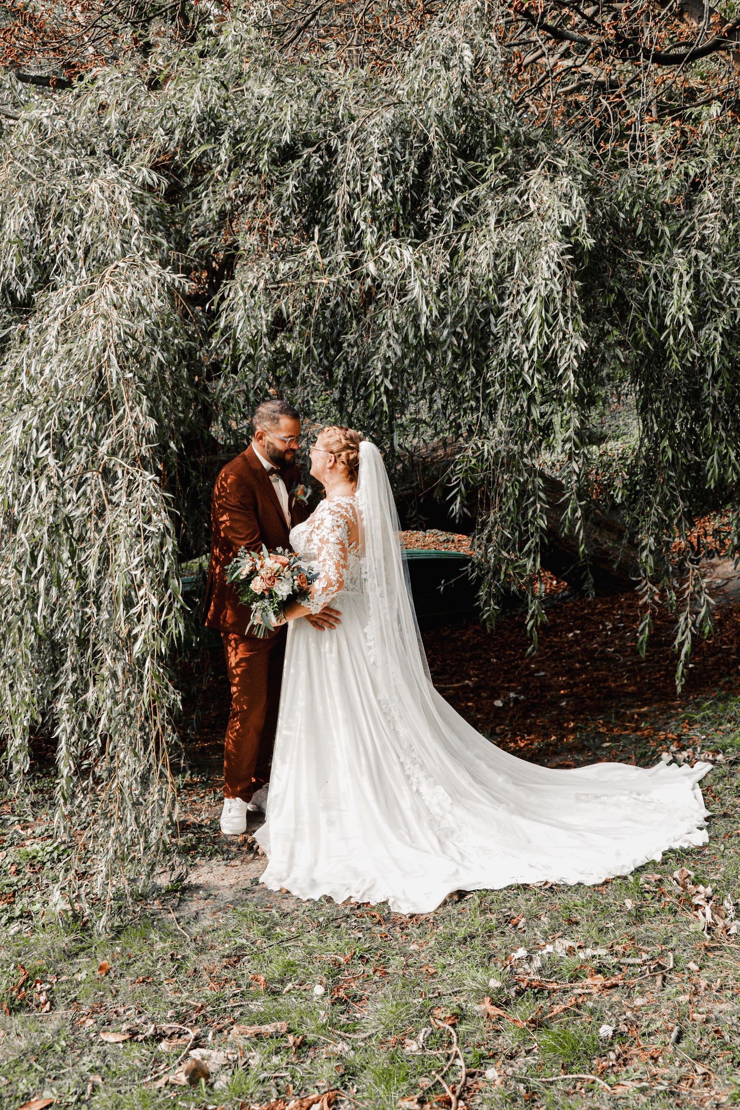 Romantic wedding portraits under weeping willow trees with flowing white dress train.