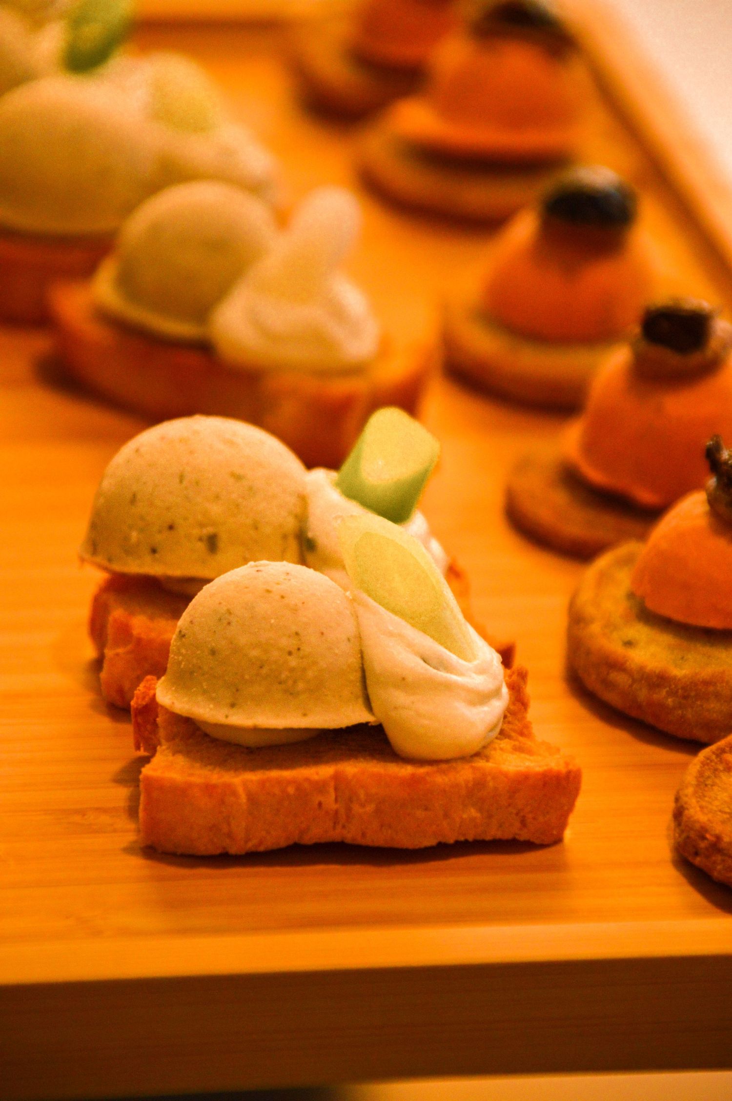 Delicate appetizers with cream spheres and garnish served on orange toast points.