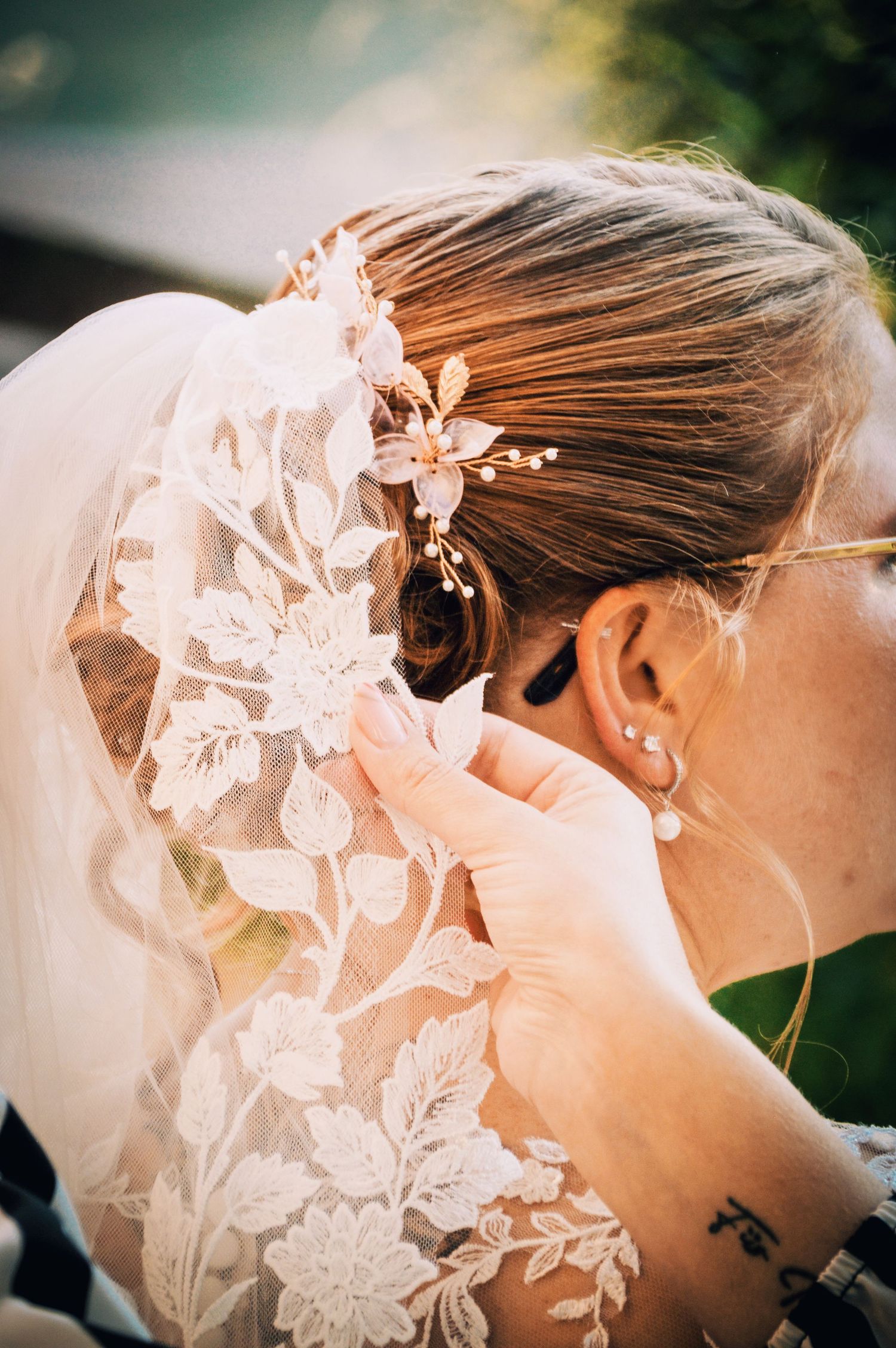 Delicate floral lace veil detail adorned with pearls in warm sunlight.