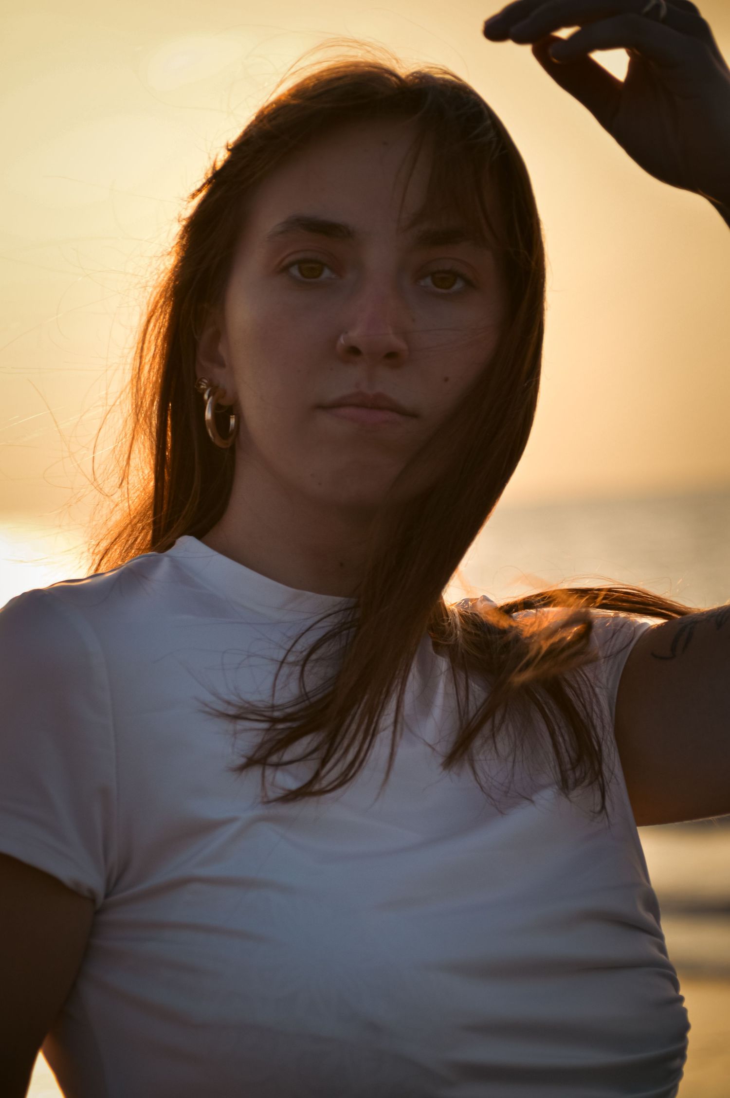 Sunset silhouette portrait wearing white t-shirt against golden sky background.