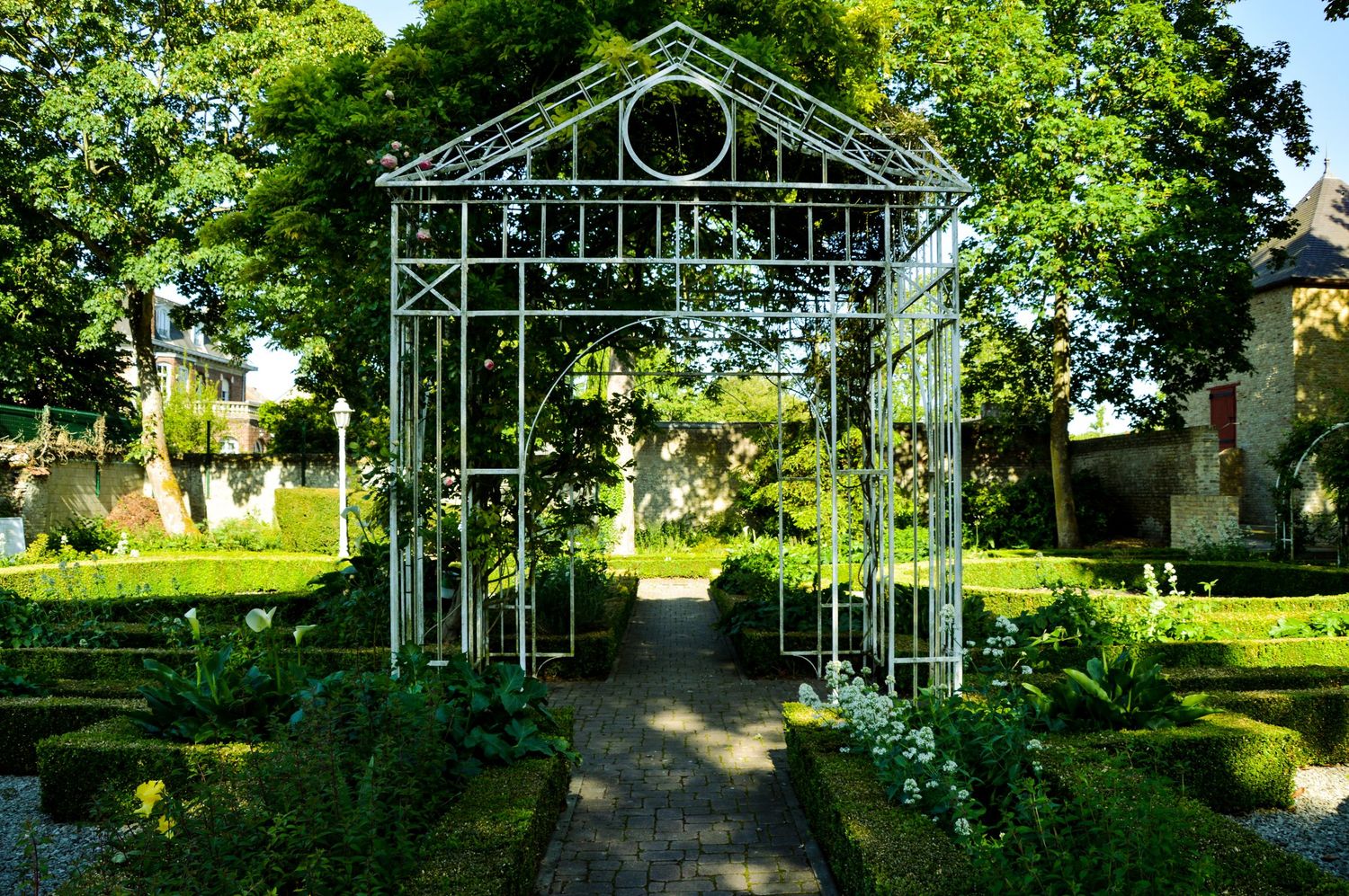 Metal garden pergolas forming a decorative walkway in a sunlit park.