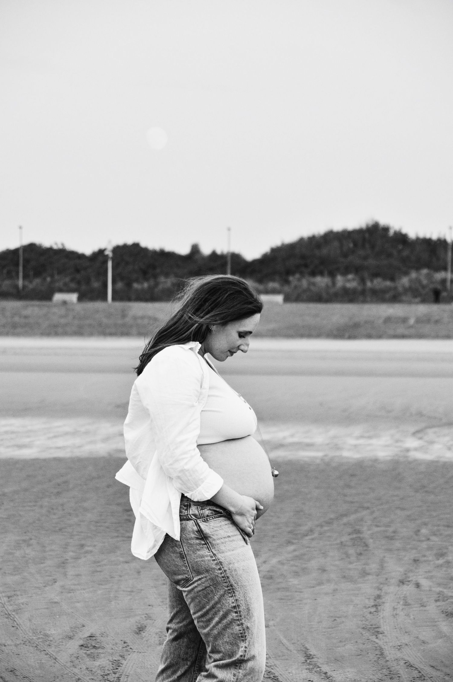 Artistic maternity silhouettes captured against a beach landscape.