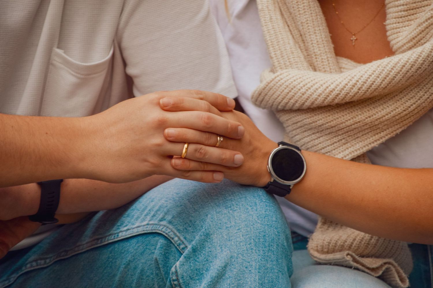 Hands gently resting on a pregnant belly while wearing a cream sweater.