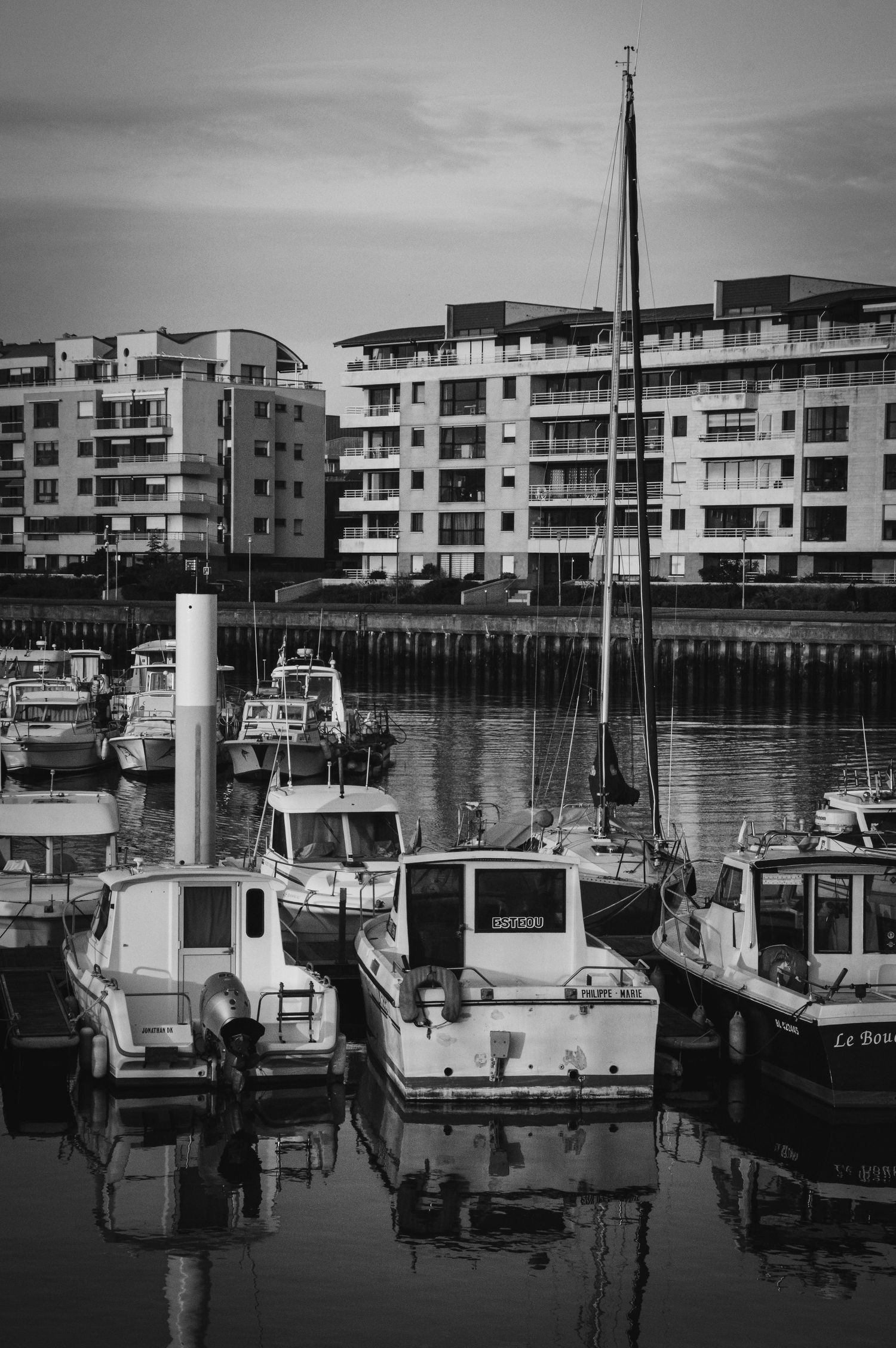 Black and white photograph of modern waterfront apartments with boats moored in marina.