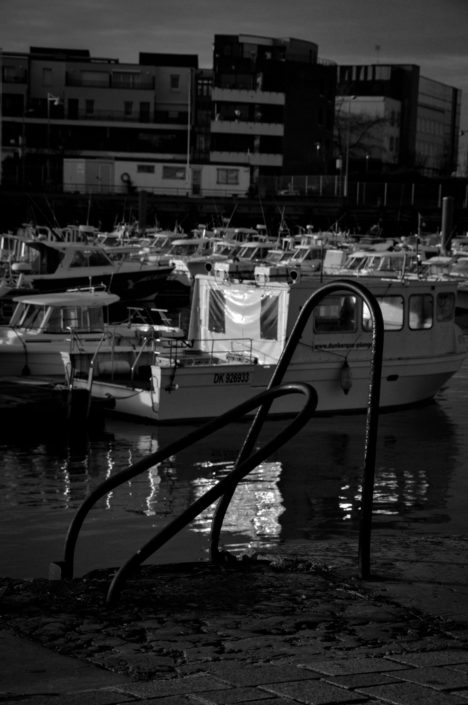 Dark silhouettes of boats in a marina against moody evening sky.