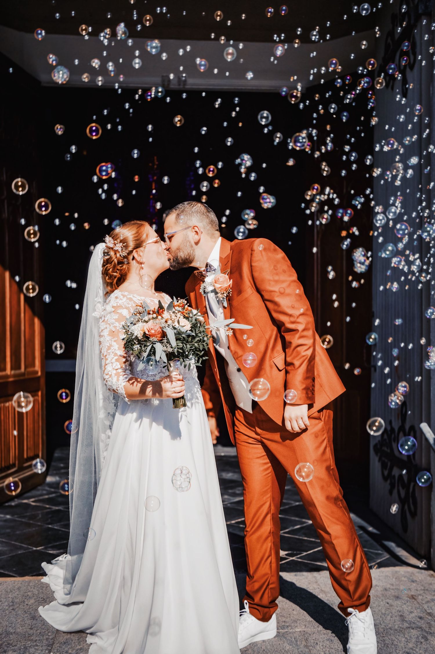 Wedding couple sharing romantic moments surrounded by floating bubbles in dramatic lighting.