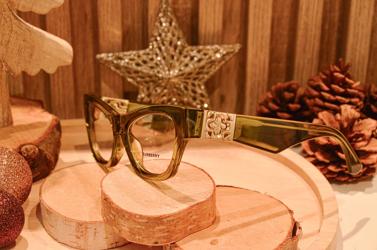 Luxury eyeglasses arranged with rustic wooden elements and holiday ornaments.