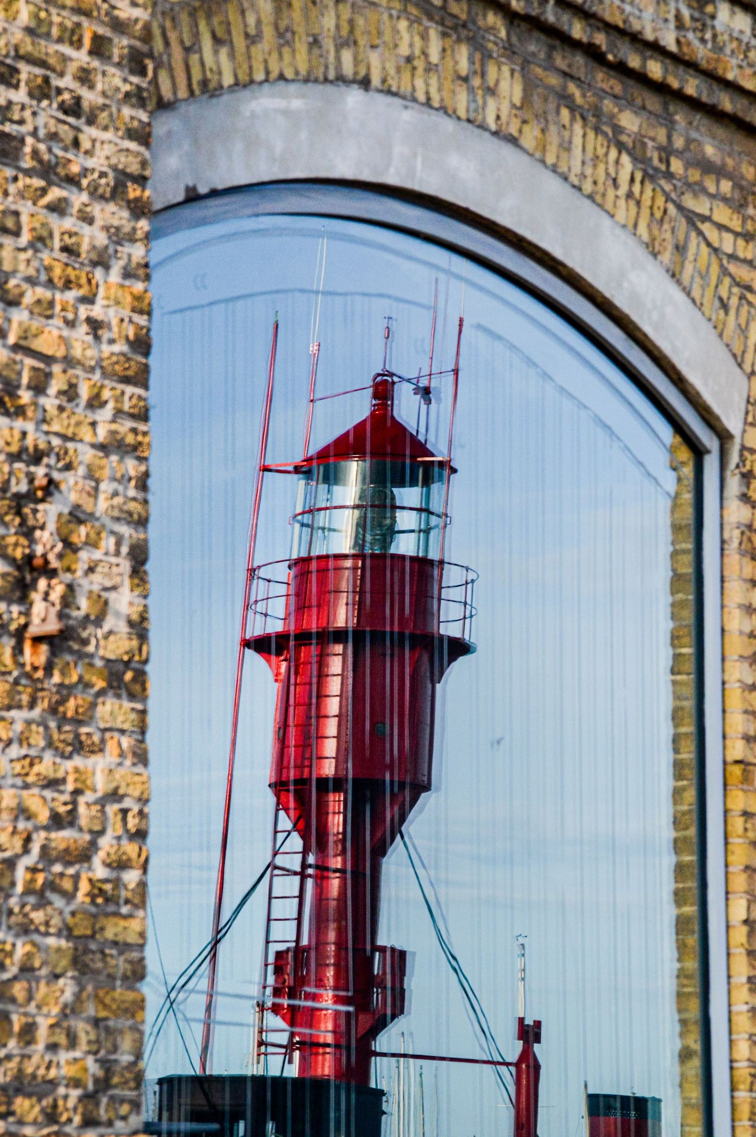 Red lighthouse mural painted on light blue wall with brick architectural framing.