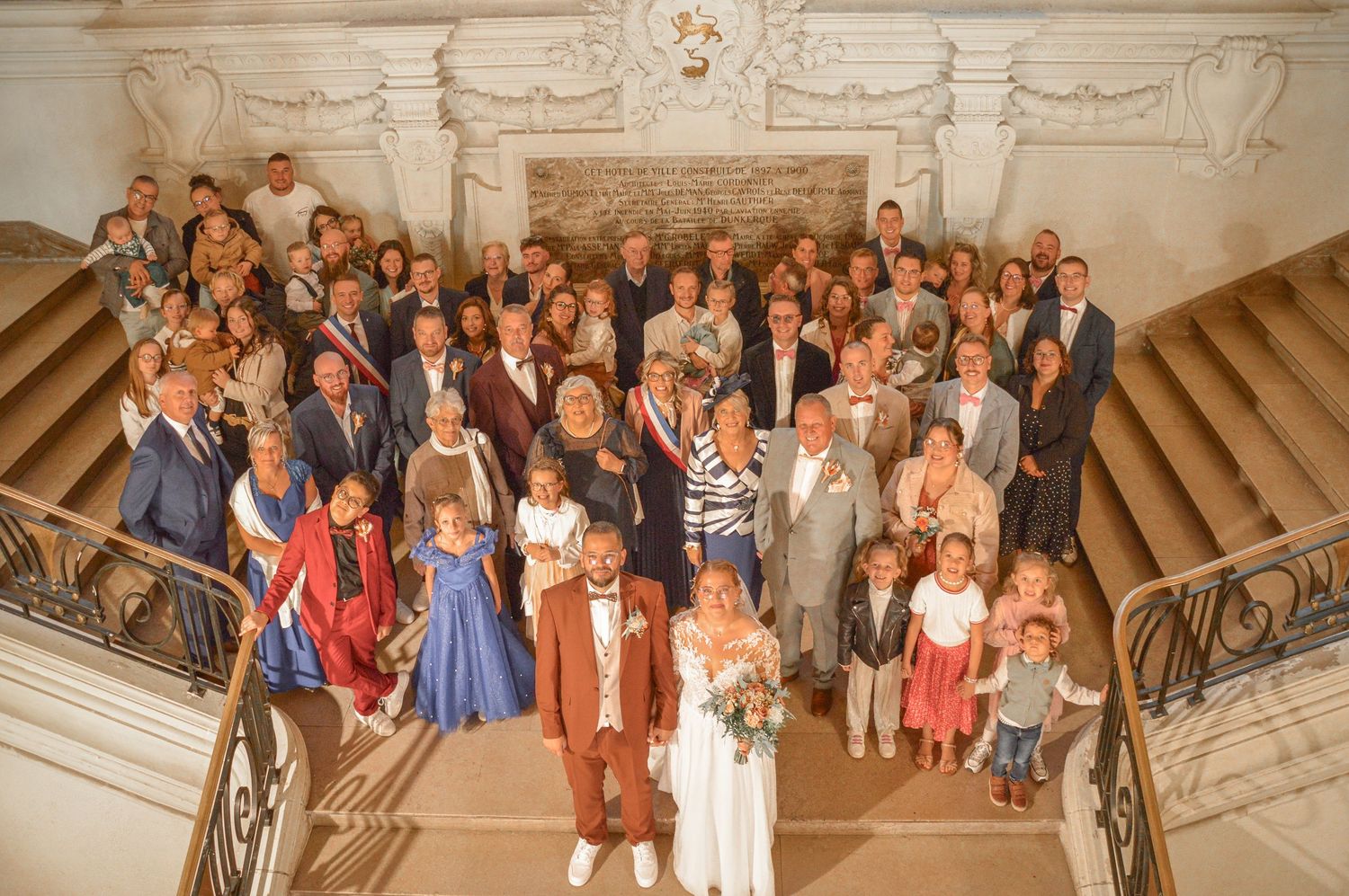 Wide angle shot of wedding guests gathered on ornate classical staircase.