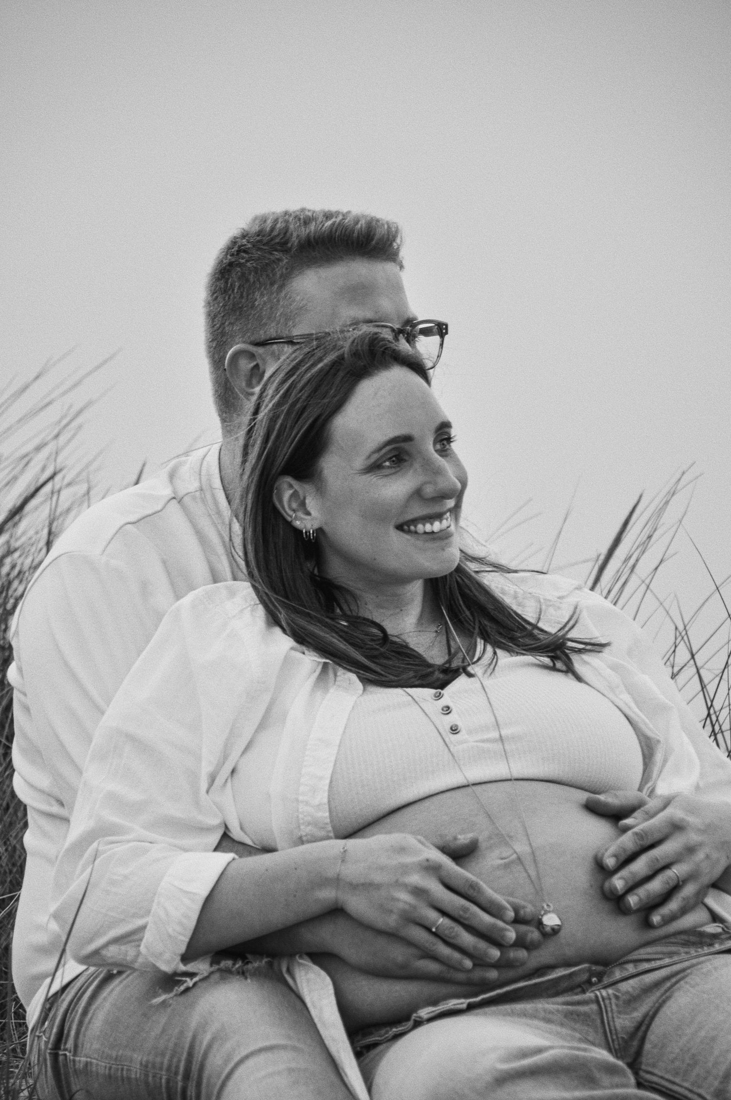 Intimate black and white portrait of couple embracing on beach.