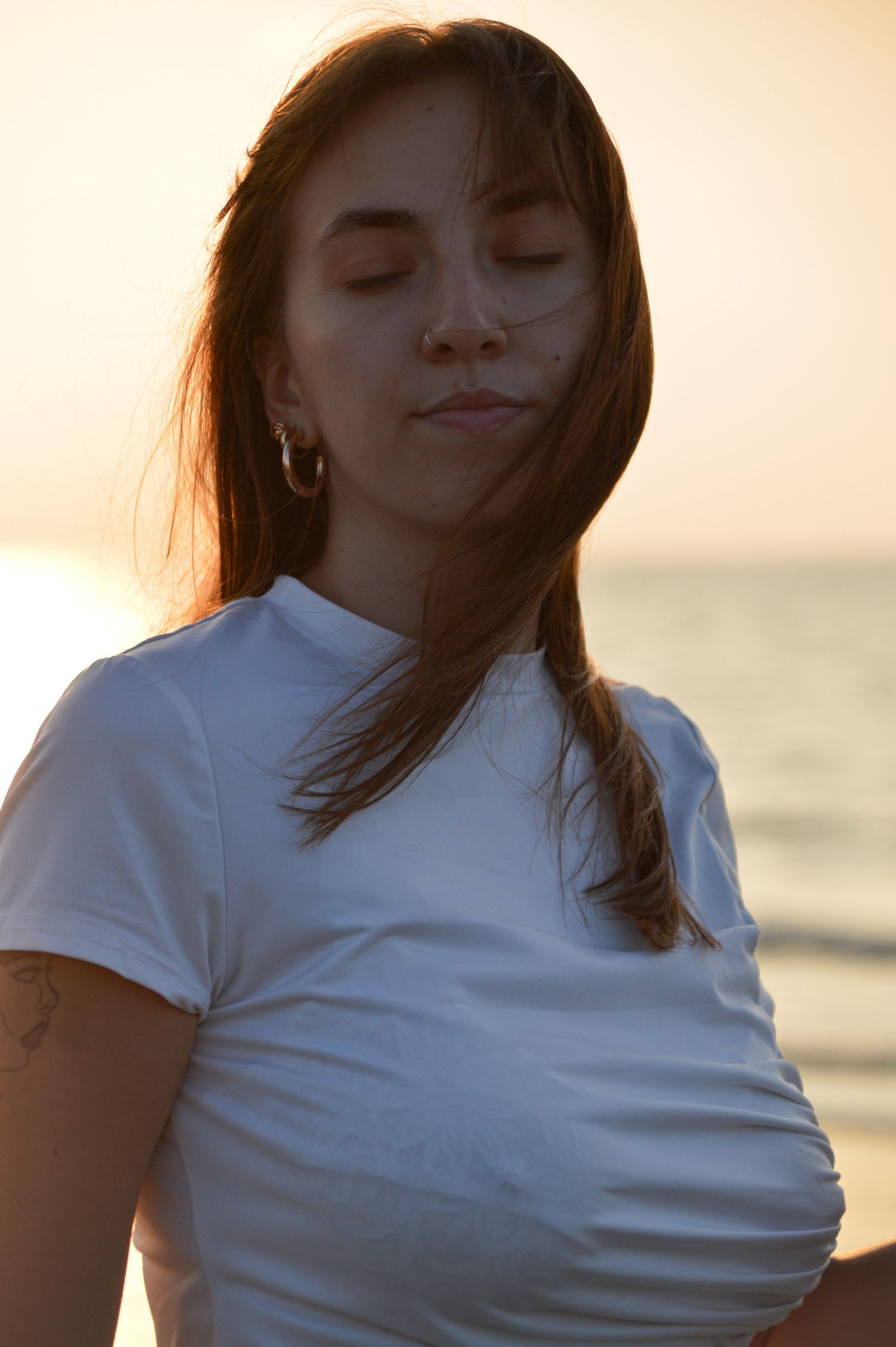 Fashion portrait at beach with warm sunset lighting and white t-shirt.