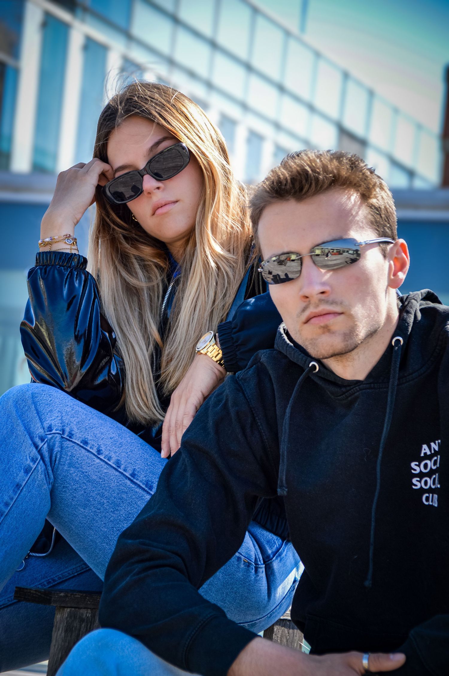 Couple in matching navy jackets resting together on sunny day.