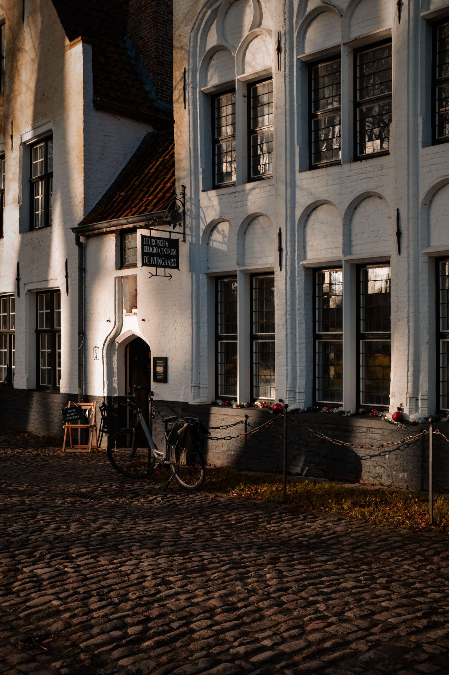 Historic white building facade with arched windows and cobblestone street in evening light.