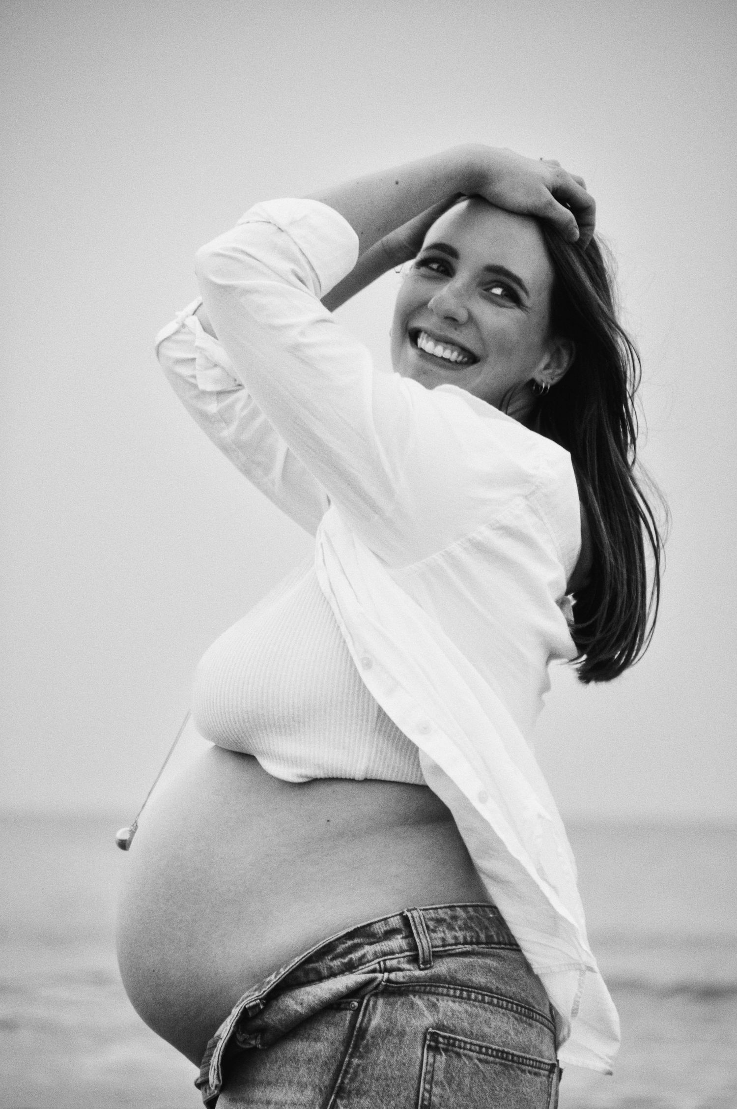 Black and white maternity portraits showing movement and joy against a light background.