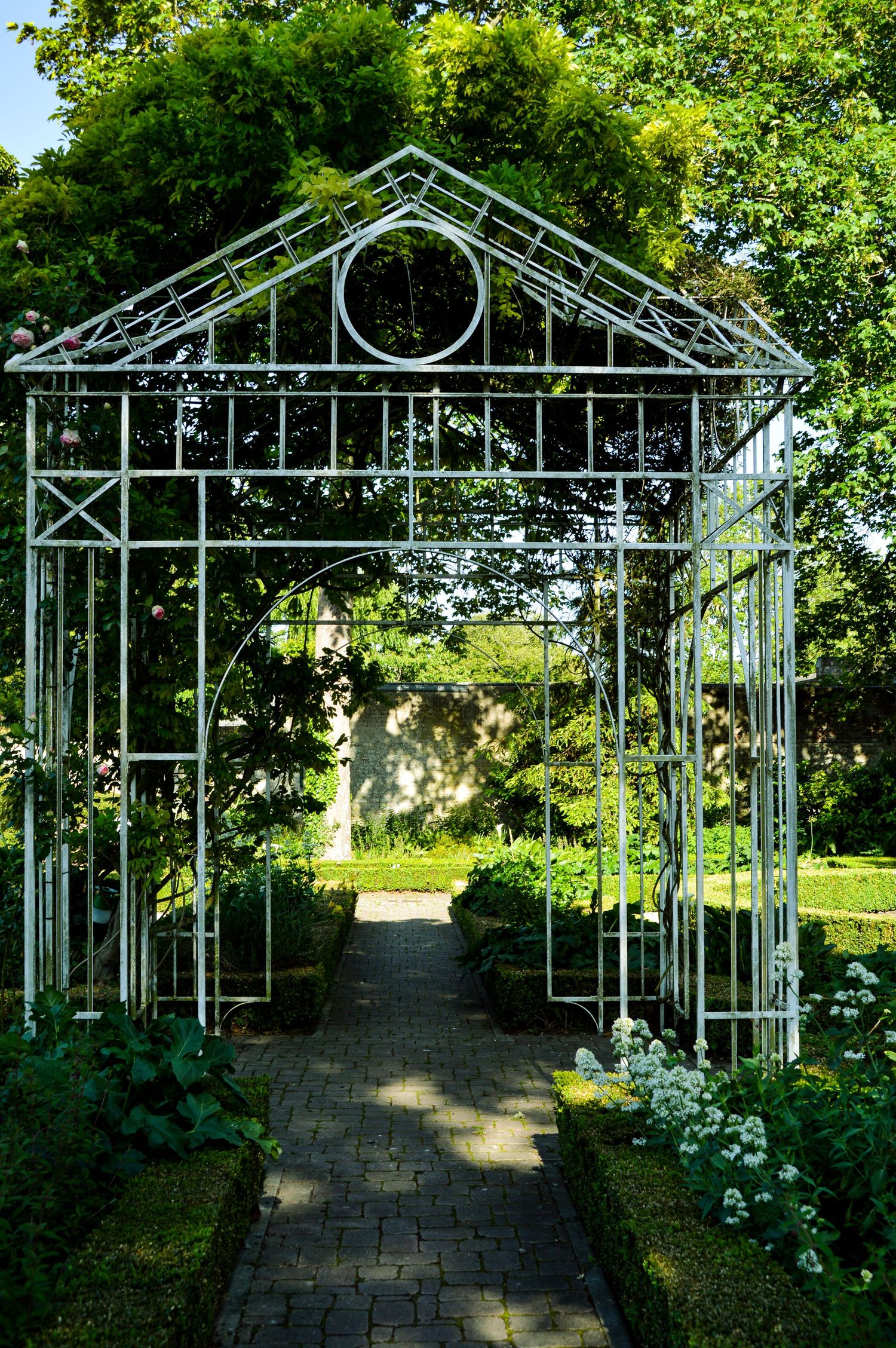 Ornate metal garden archways creating a pathway through lush greenery.